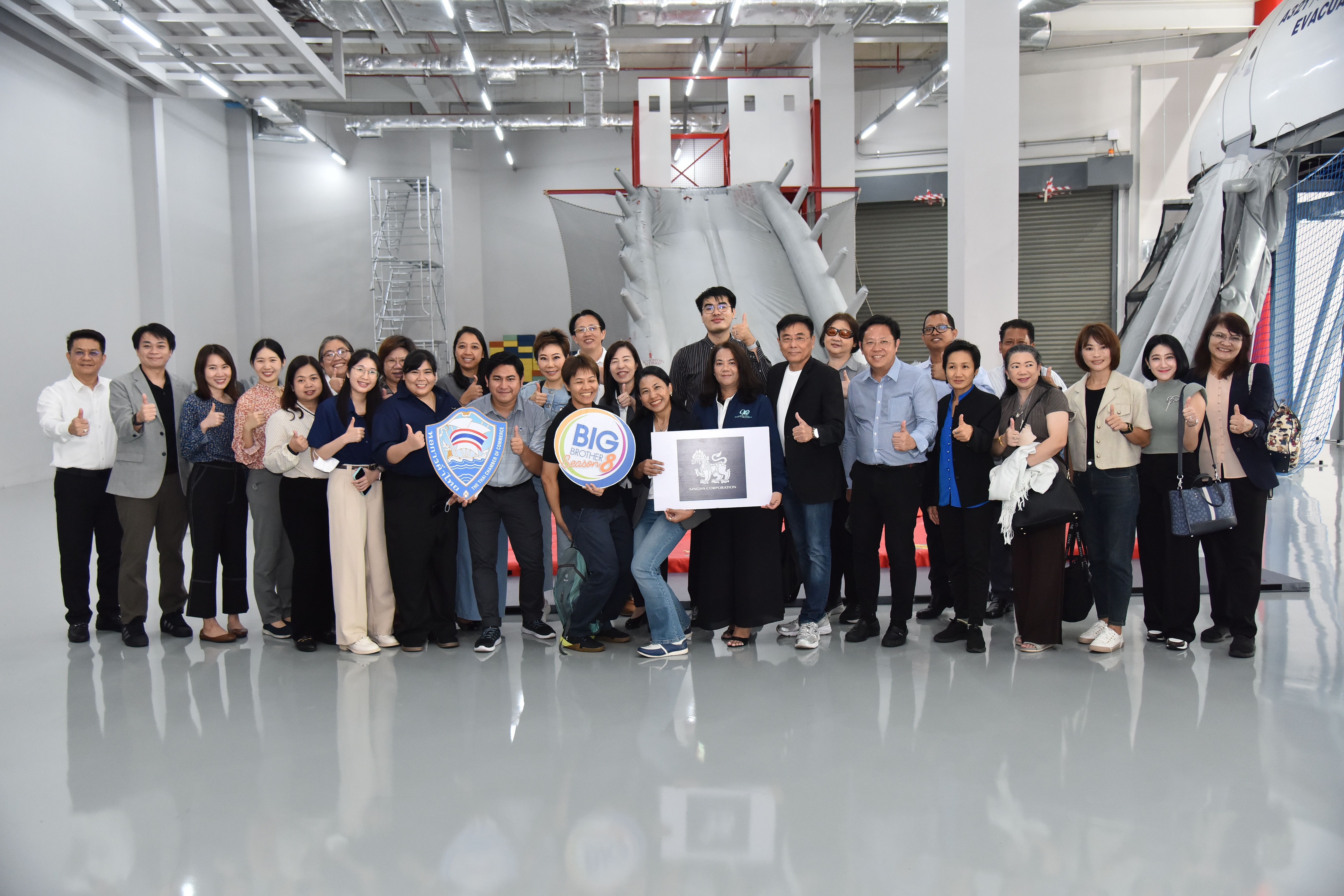 Large group of professionals posing with awards and signs in a modern industrial setting.