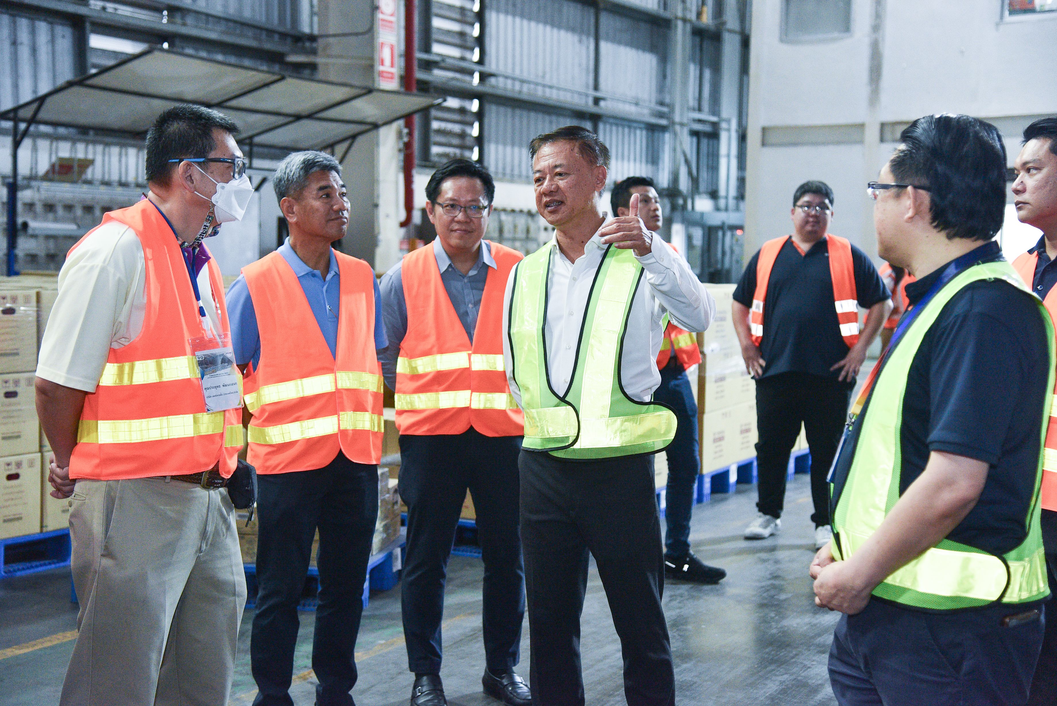 Group of men in safety vests discussing logistics inside a large warehouse.