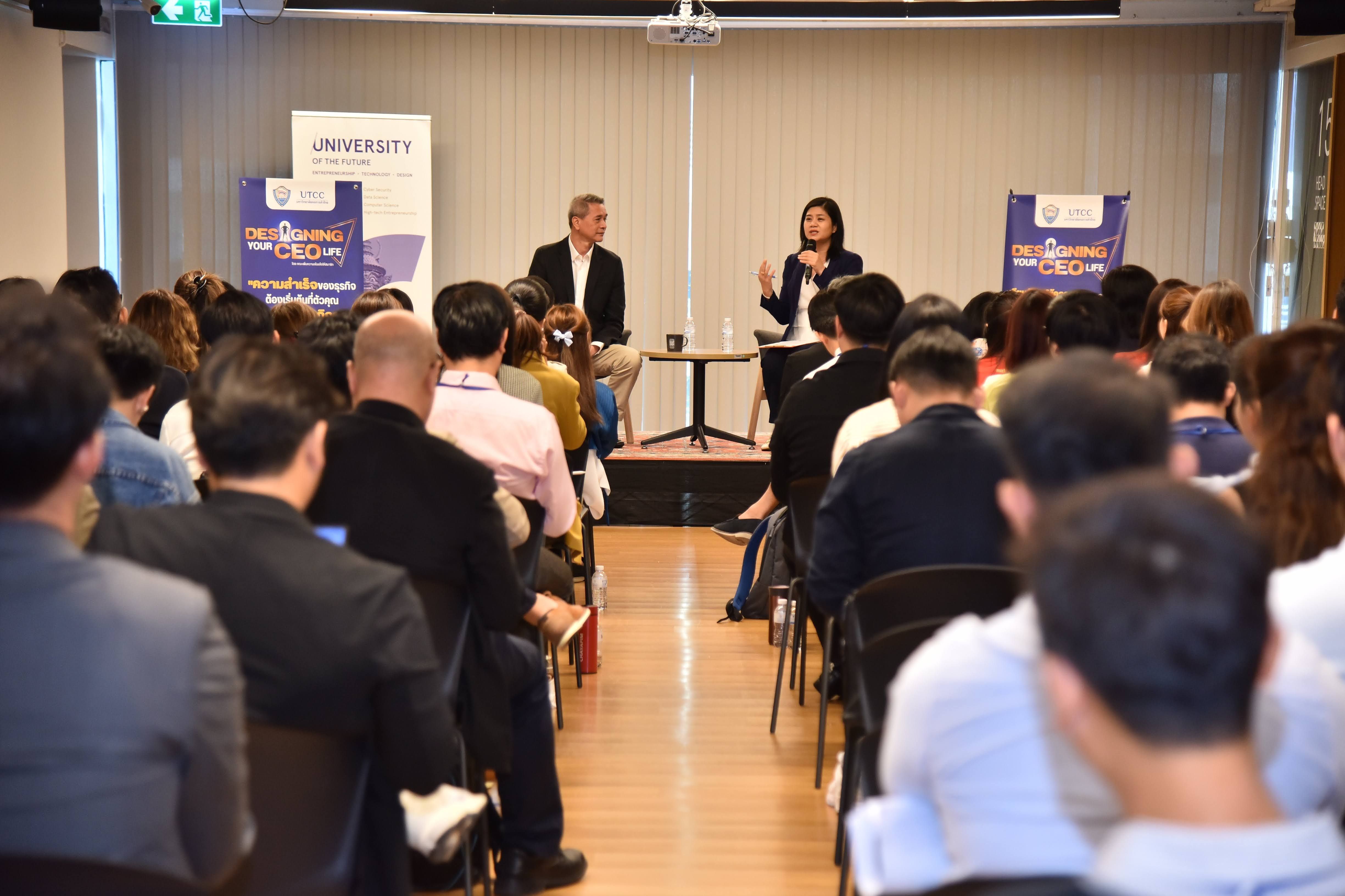 Two speakers address a seated audience at a professional conference with banners in background.