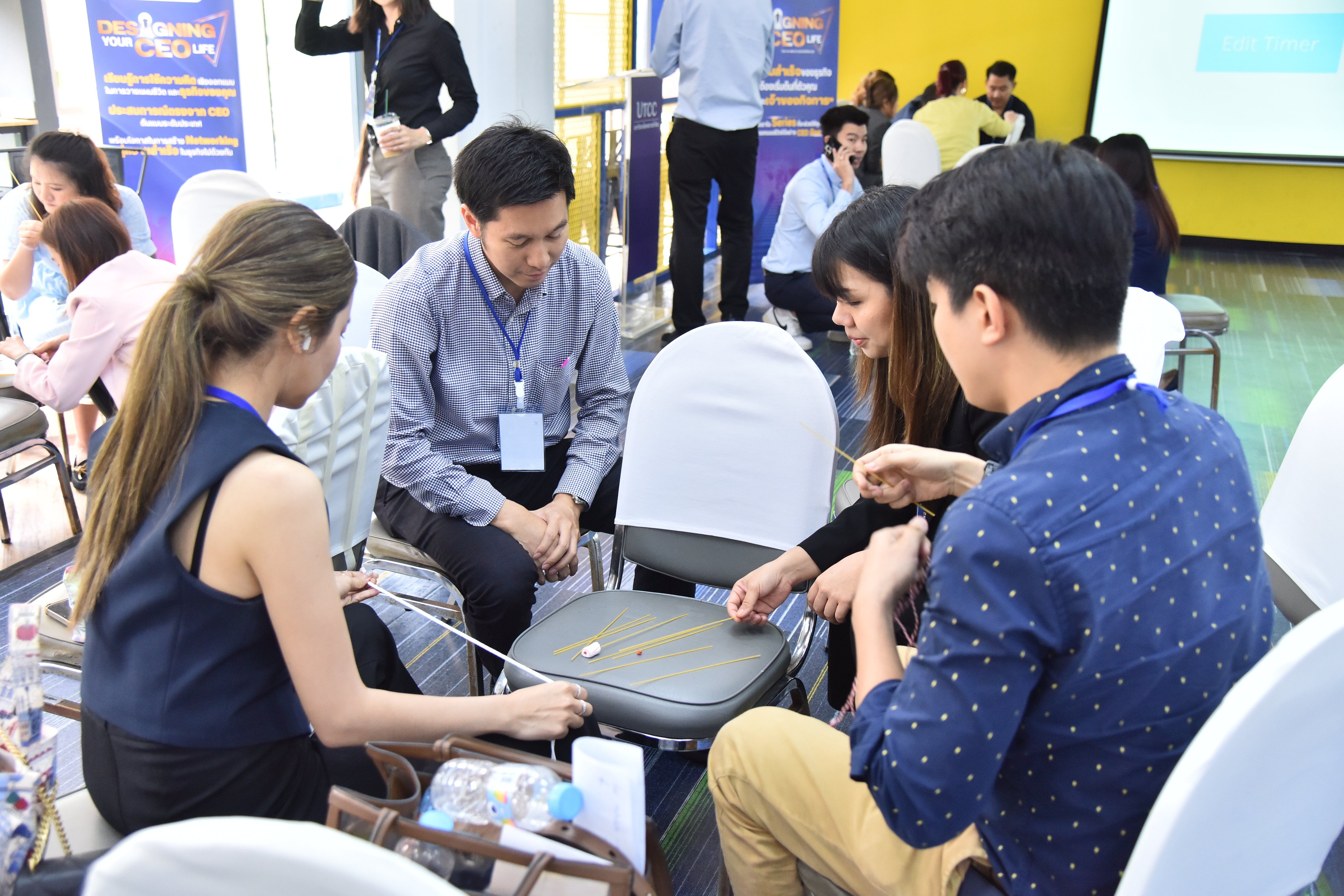 Four young adults intently examine a yellow necklace during a collaborative group activity.