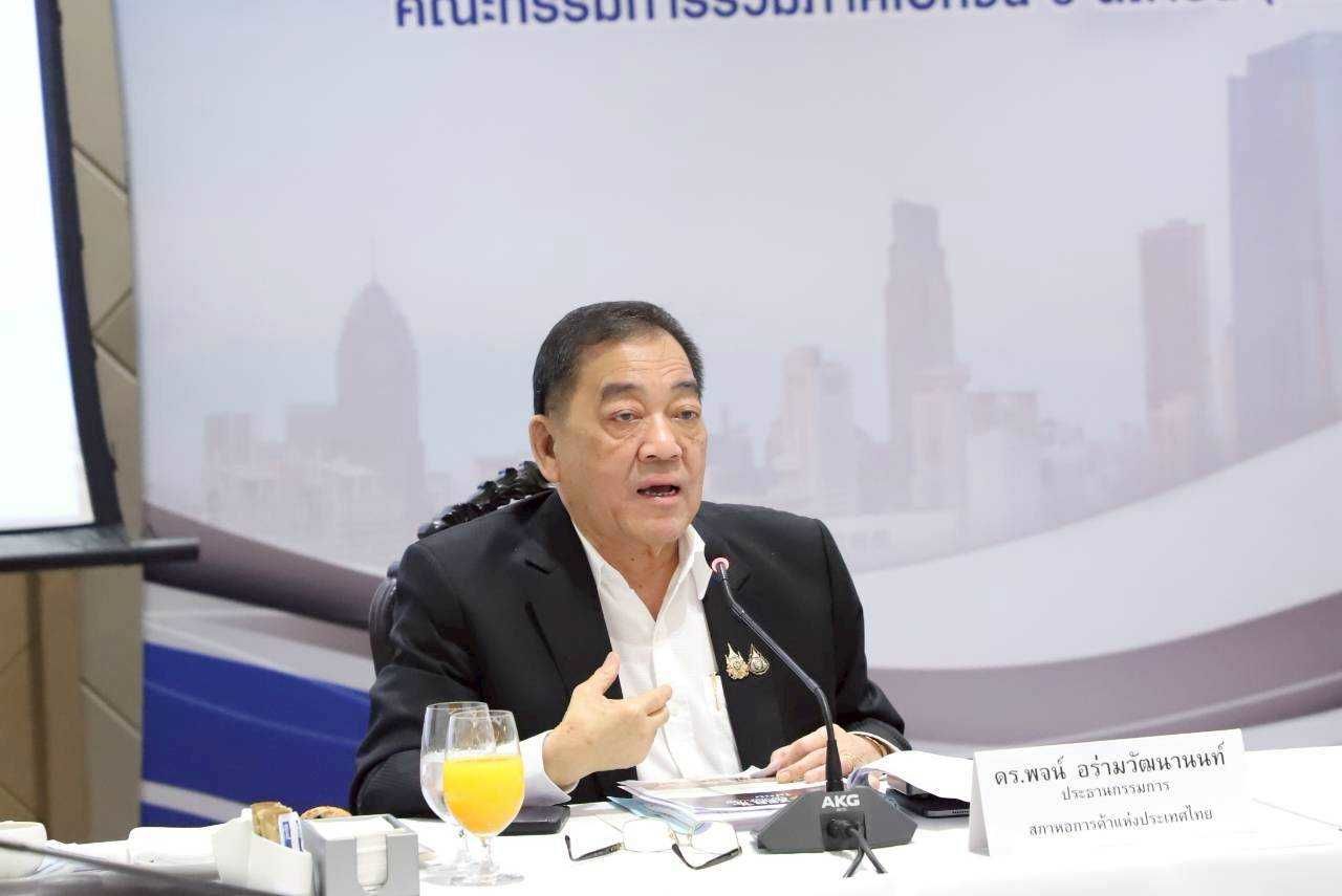 Asian man in a suit jacket speaks at a table with a microphone.