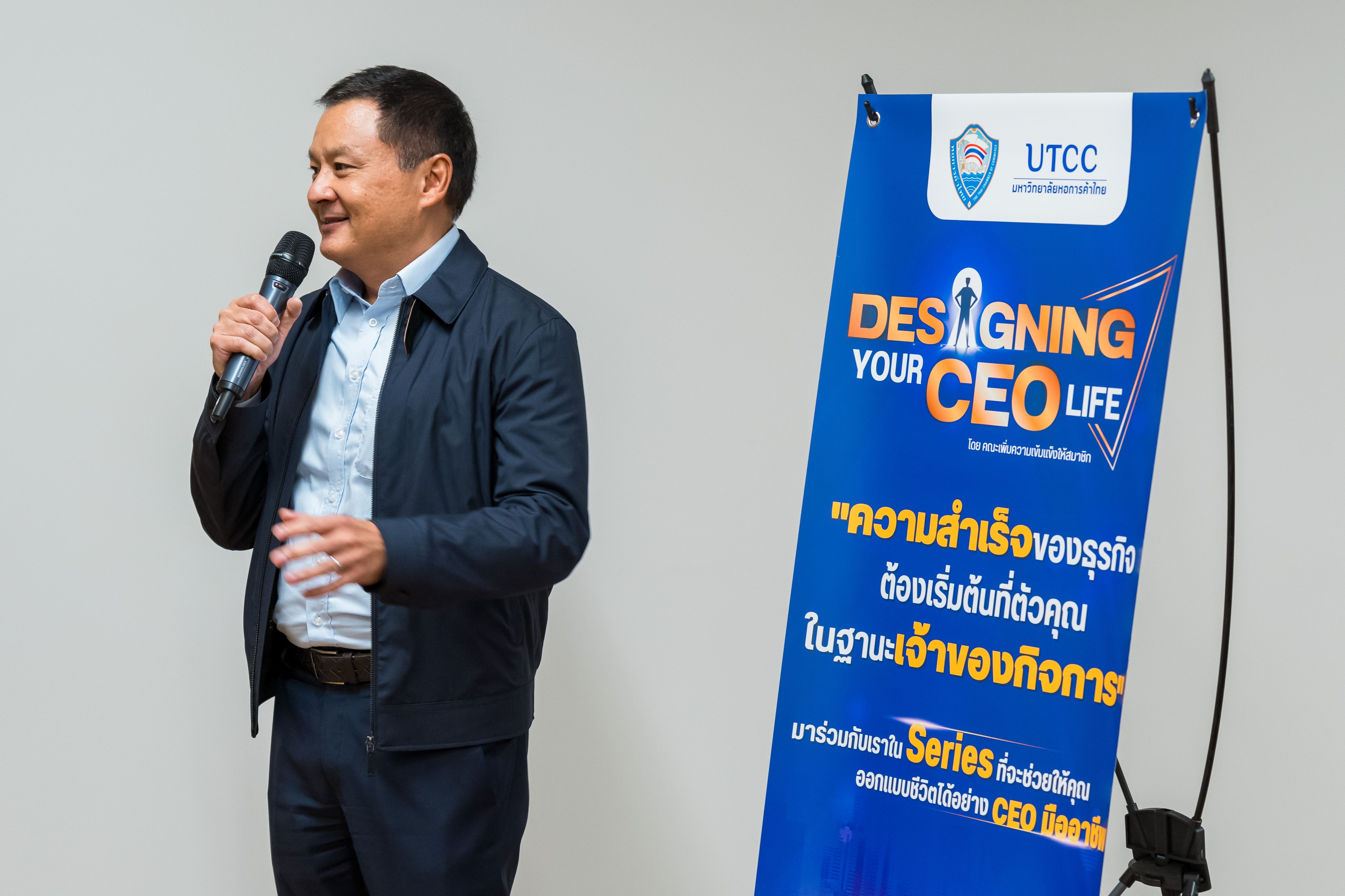 Man speaking into microphone next to blue banner displaying 'Designing Your CEO Life'.