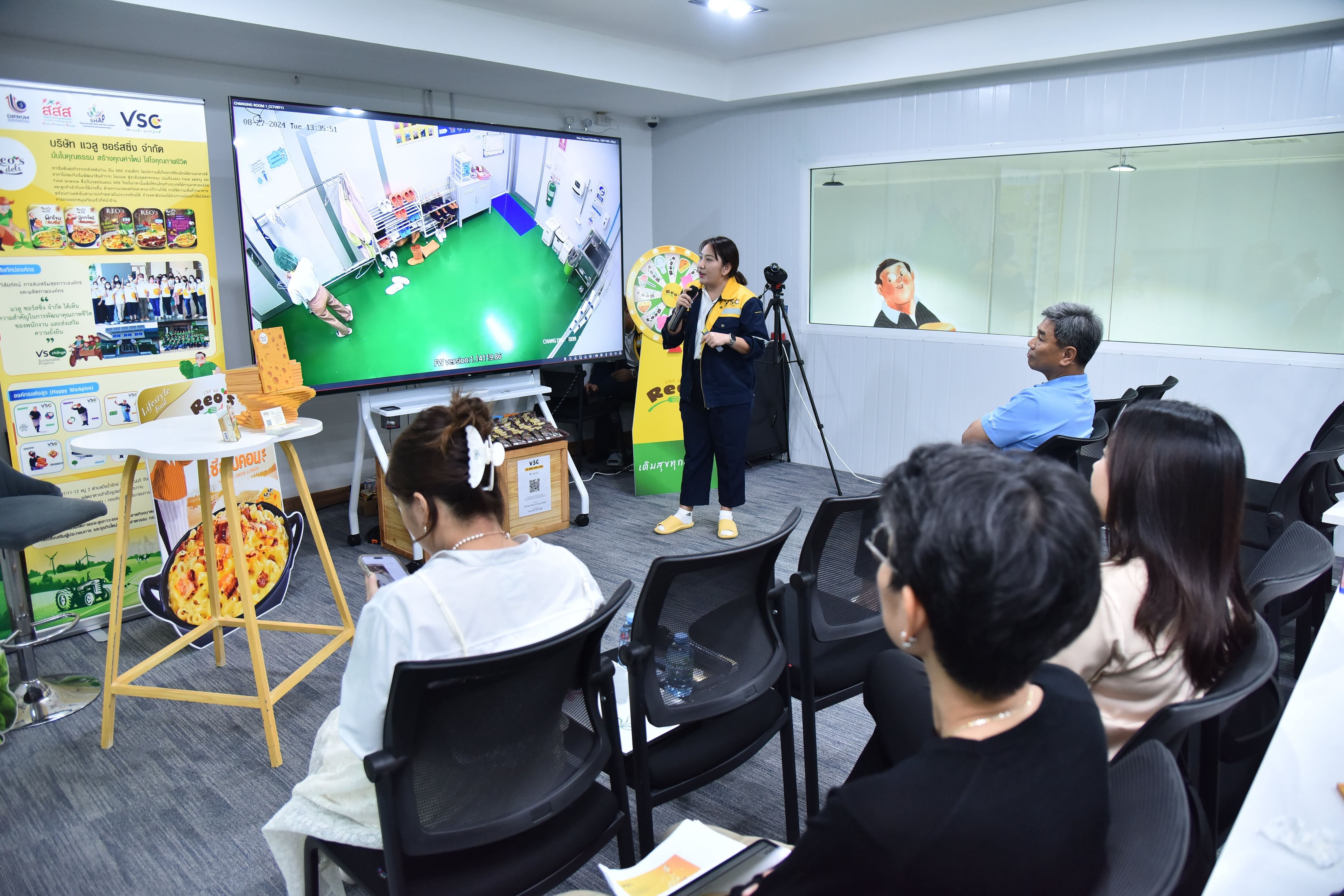 Woman presents a virtual golf course on a large screen to an attentive audience.