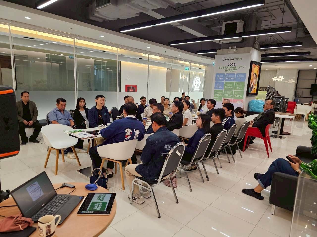 Group of professionals seated around tables in a modern office meeting space.