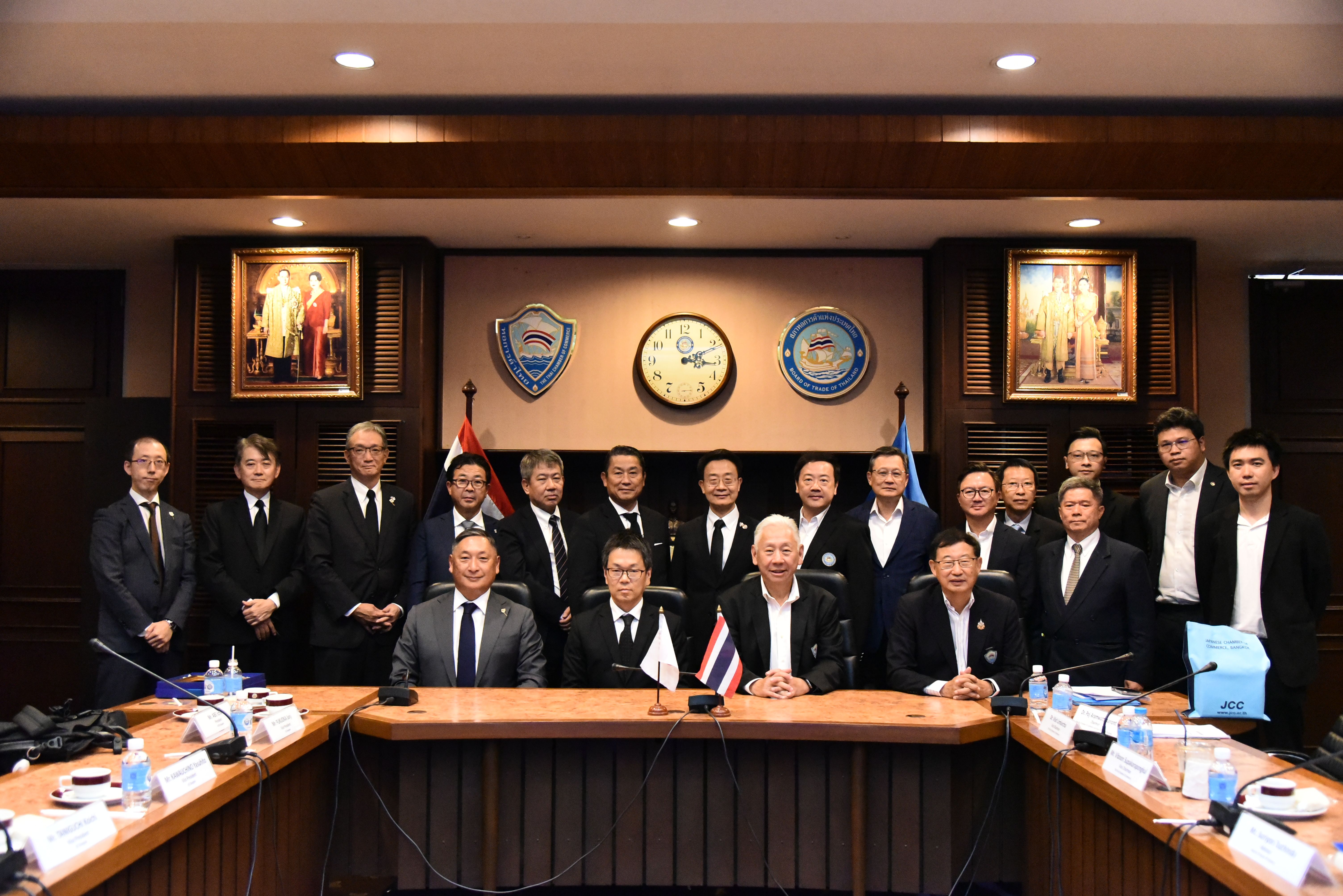 Group of business officials in suits posing for a photo in a professional conference room.
