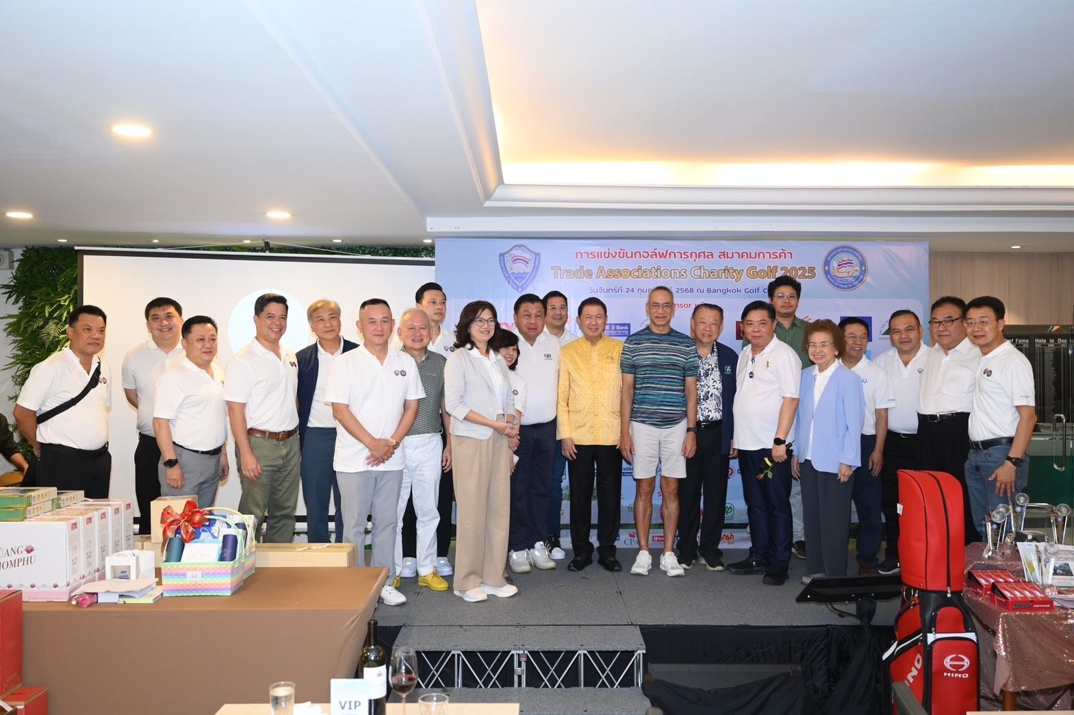 Group of attendees posing together on a stage at an indoor event with prizes.