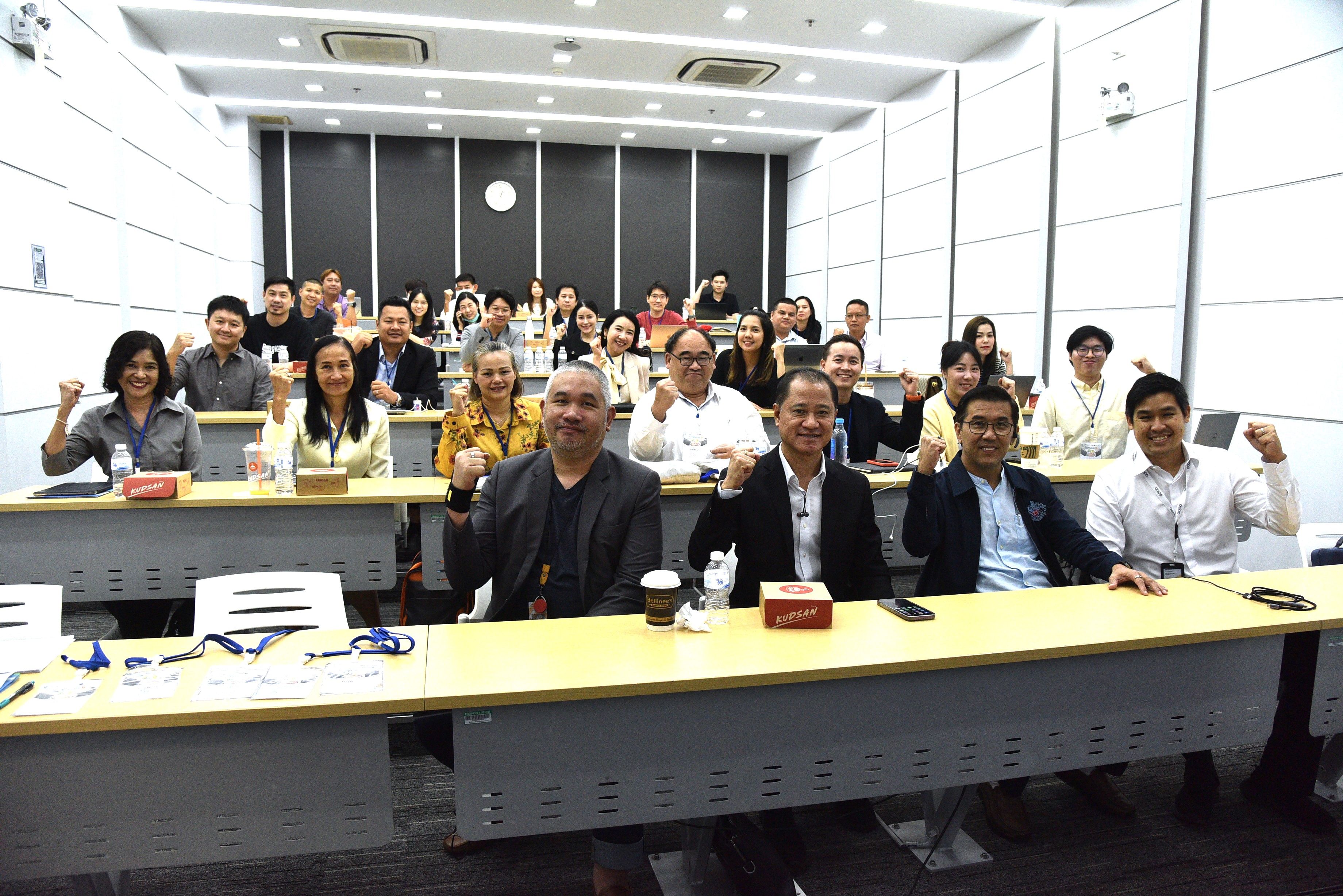 Diverse group of participants in a training seminar raising their fists enthusiastically.