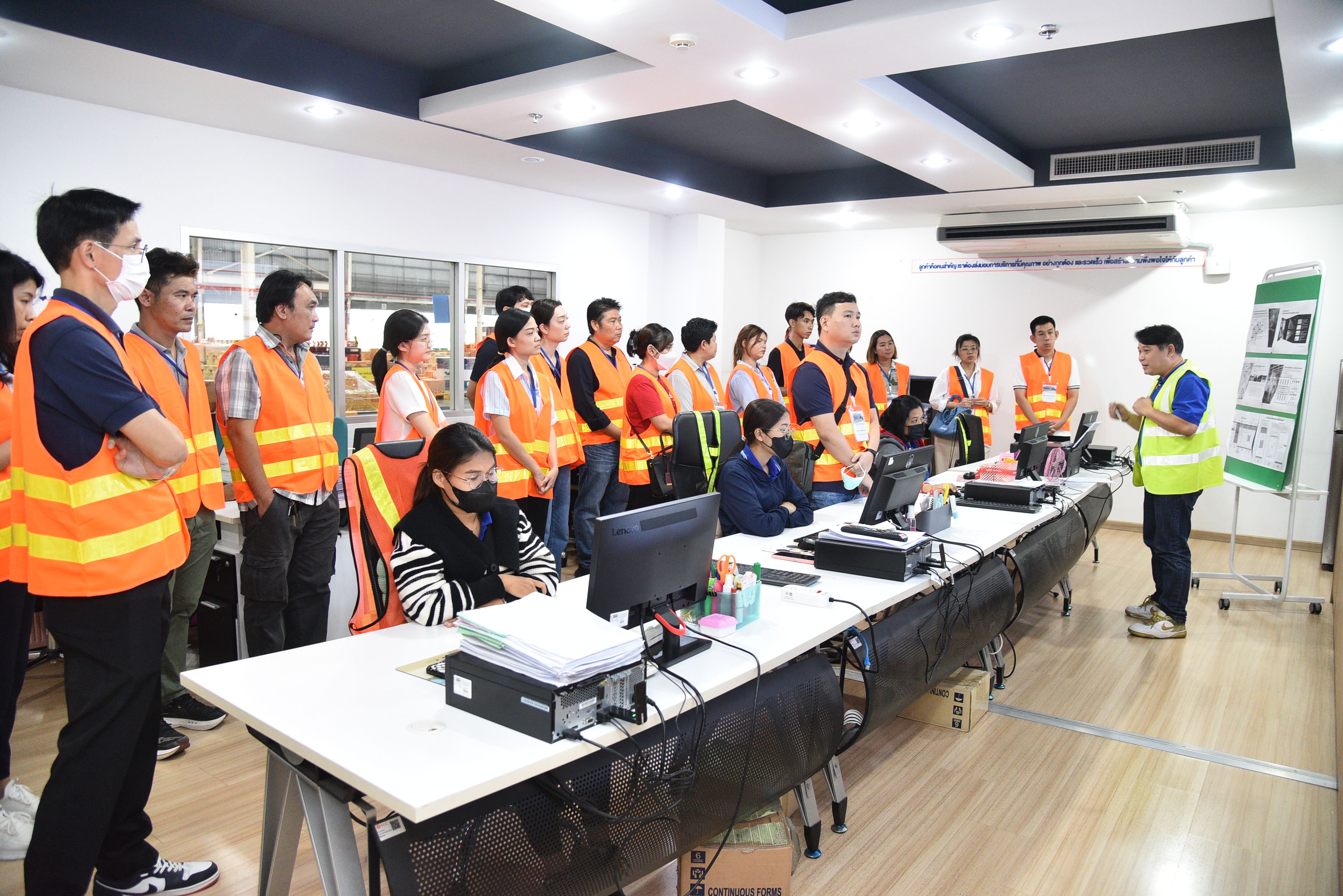 Group in orange safety vests attending a presentation in a modern training room.