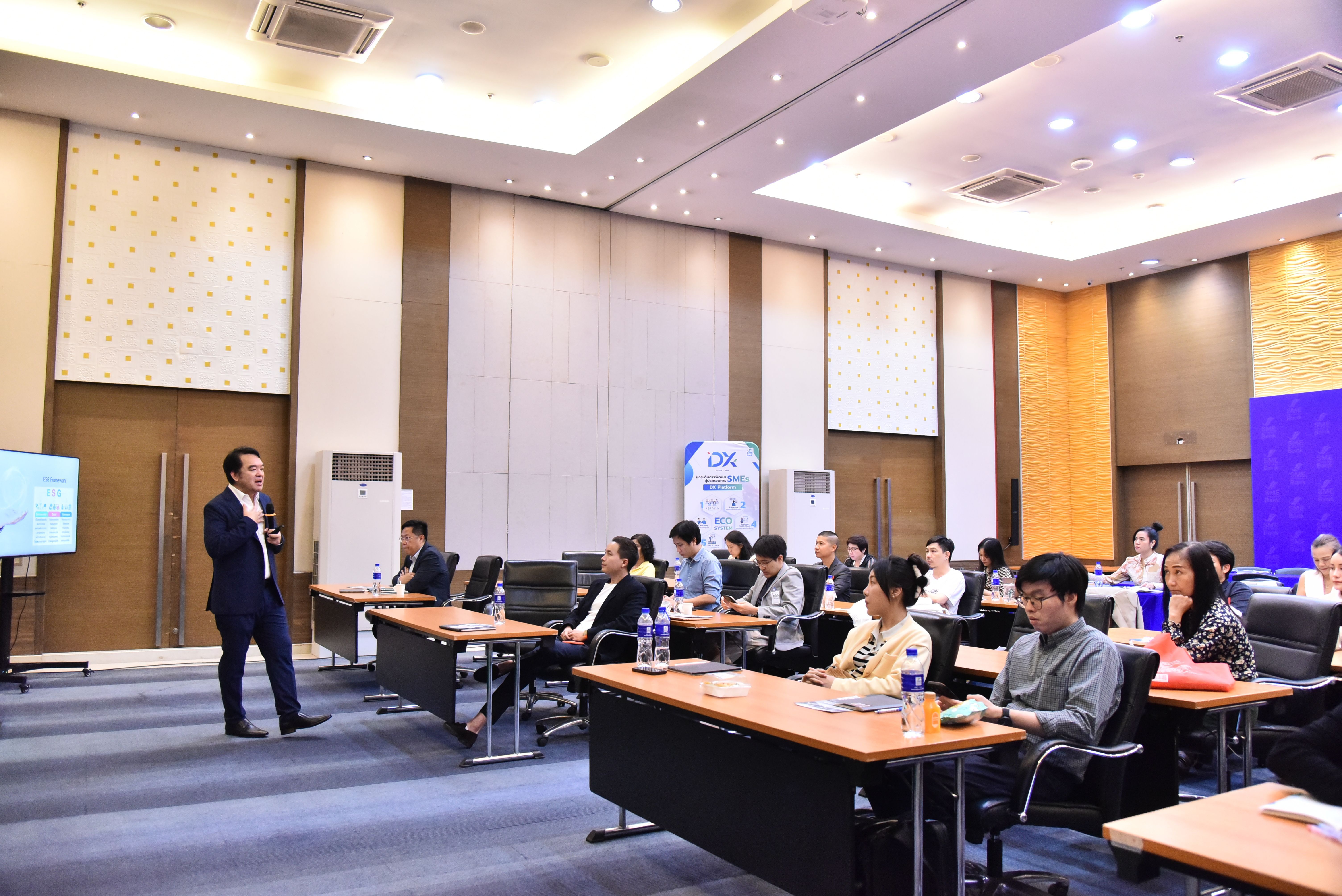Man in suit presents to an attentive audience in a modern conference room.