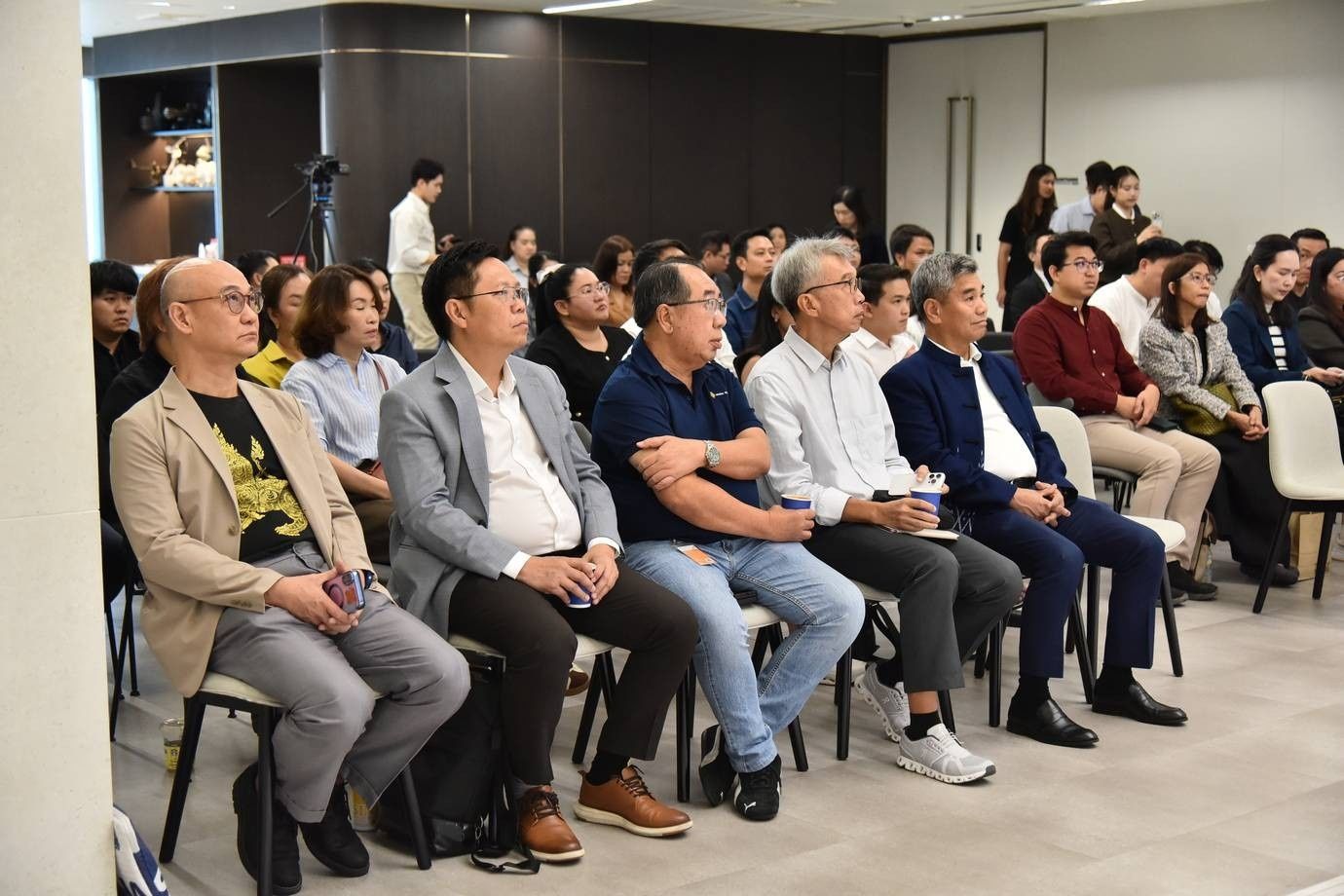 Diverse group of attendees listens intently at an indoor business event.