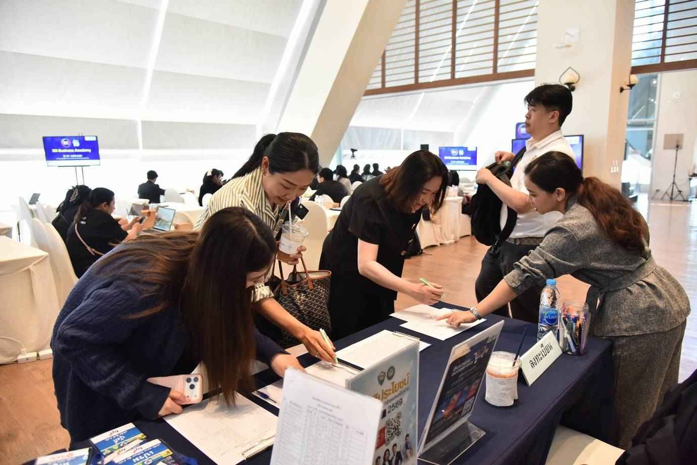 Attendees registering at a busy event desk, filling out forms and interacting with staff.