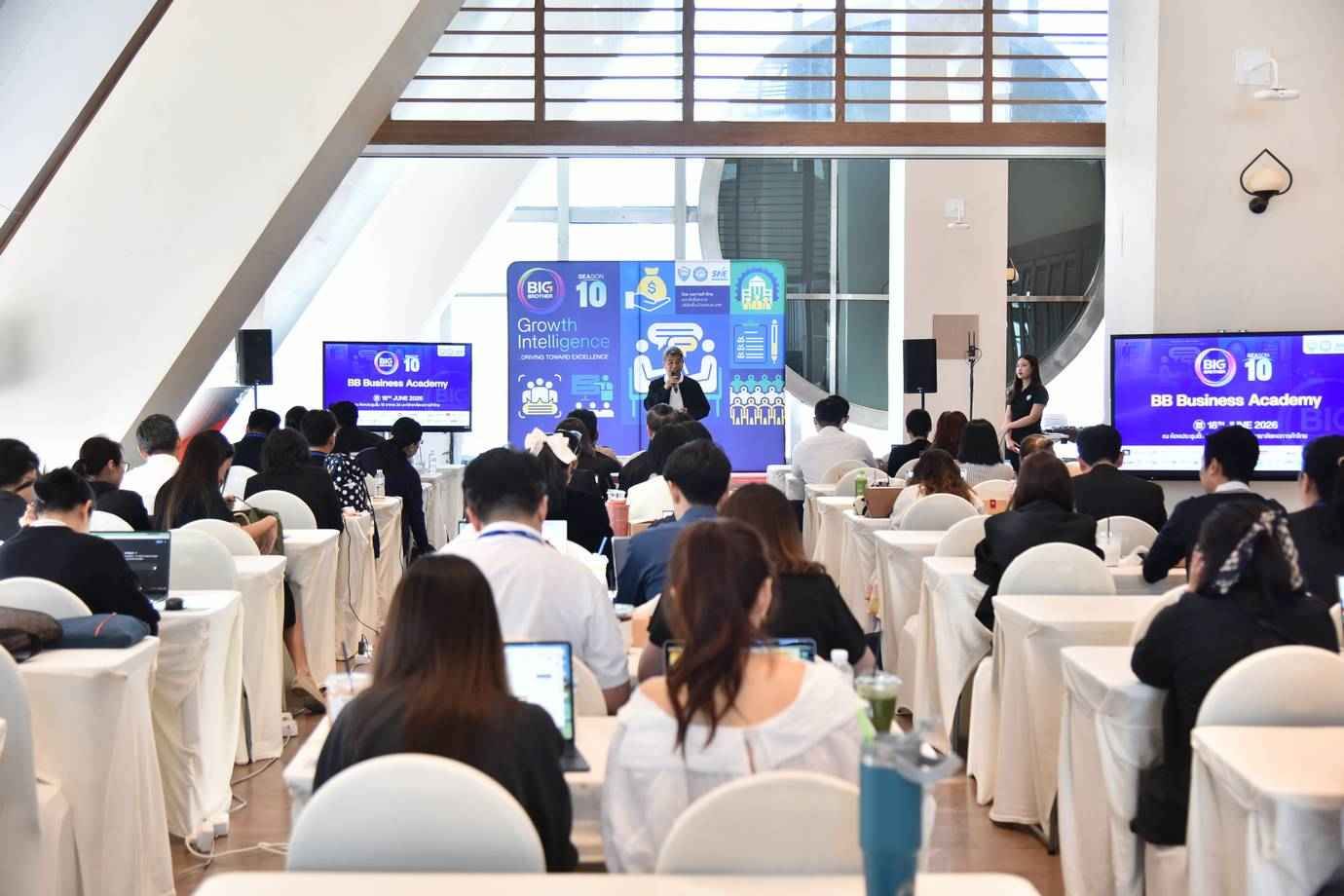 A speaker presents to a large audience at a Huawei Academy conference.