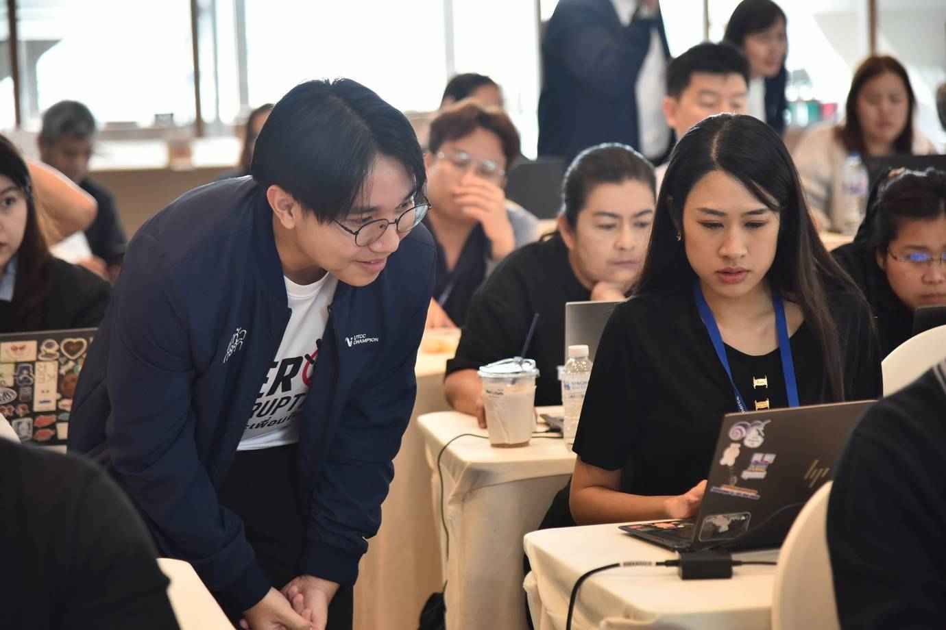 Two individuals, a man and a woman, collaborating and looking at a laptop screen in a professional setting.