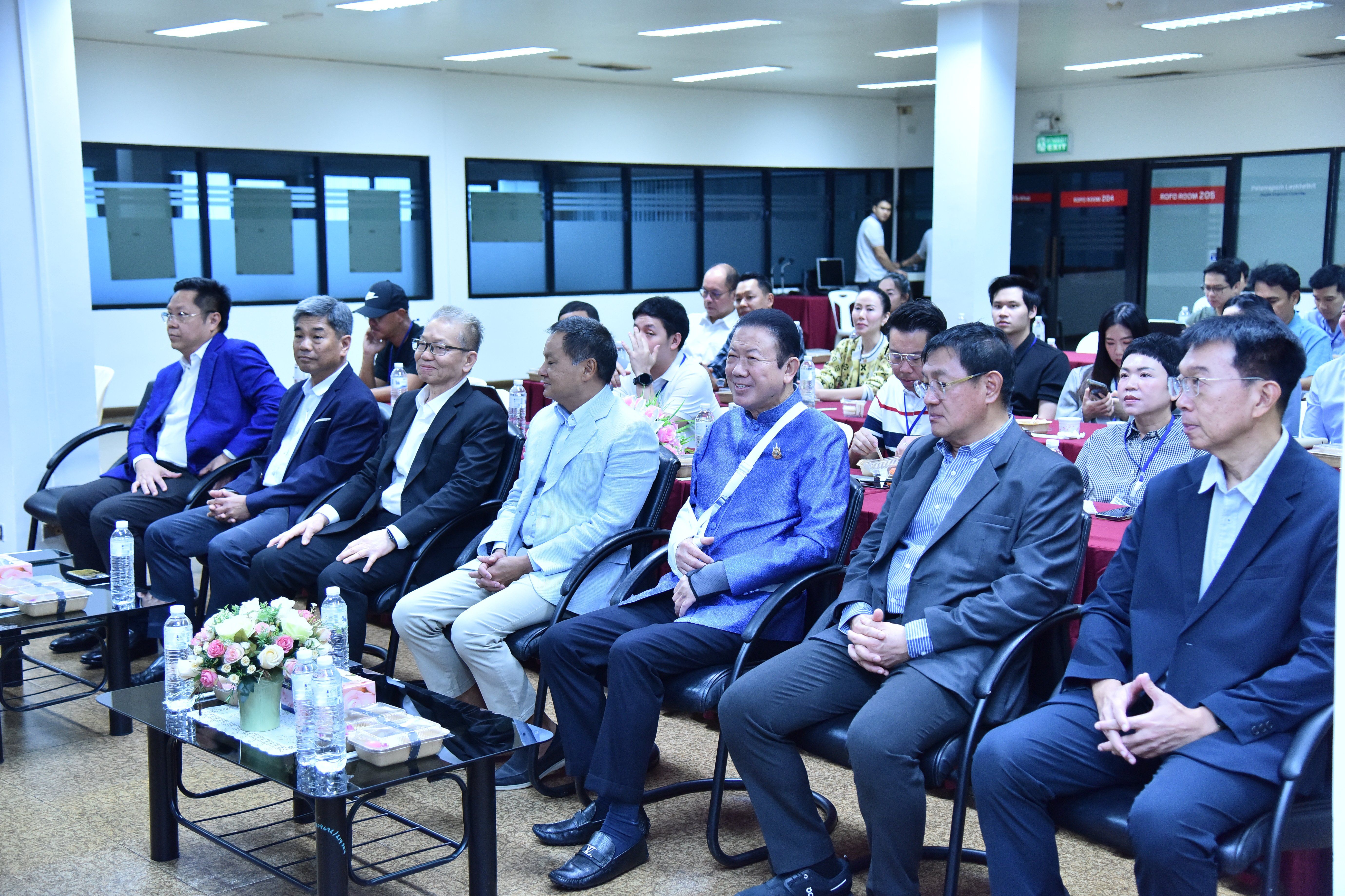 Diverse group of men in formal attire seated in rows attending a conference presentation.