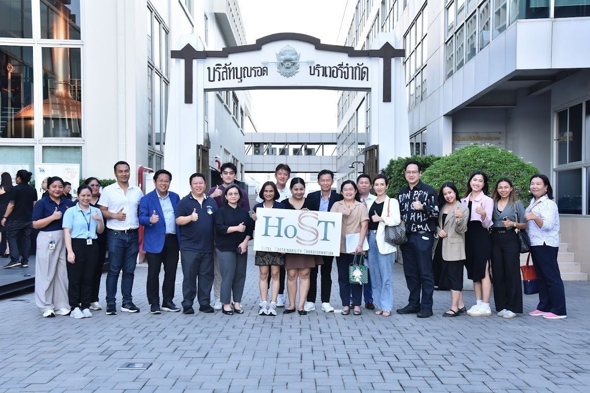 A group of diverse professionals smiling with a HoST sign in front of a building.