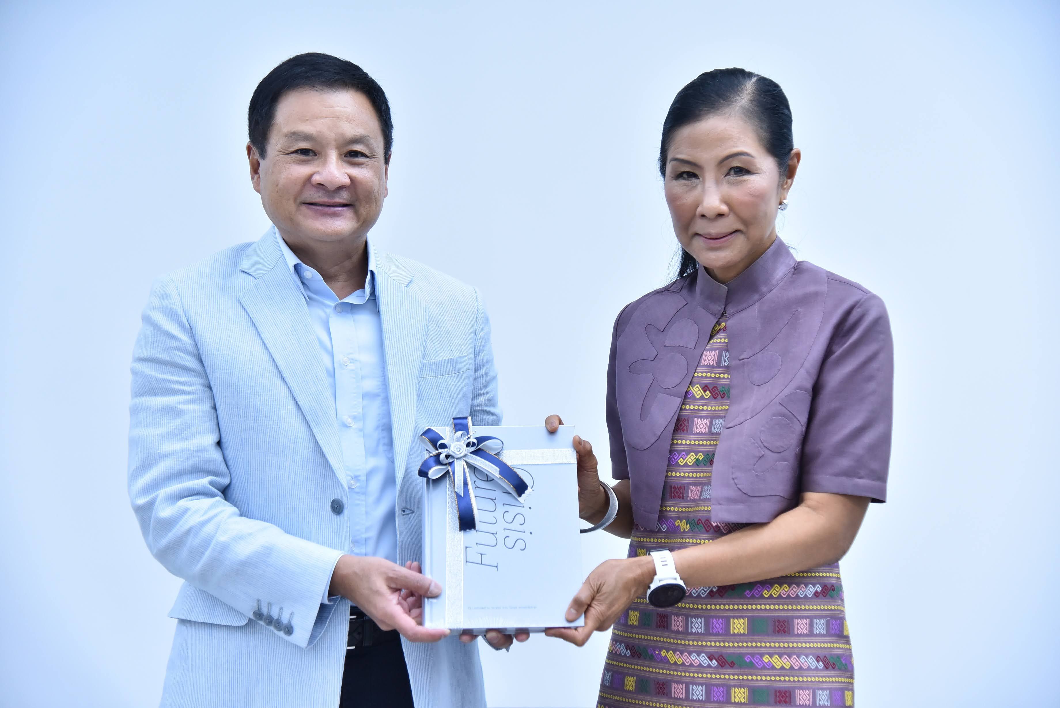 Man in light blue jacket and woman in purple top hold a white gift bag.
