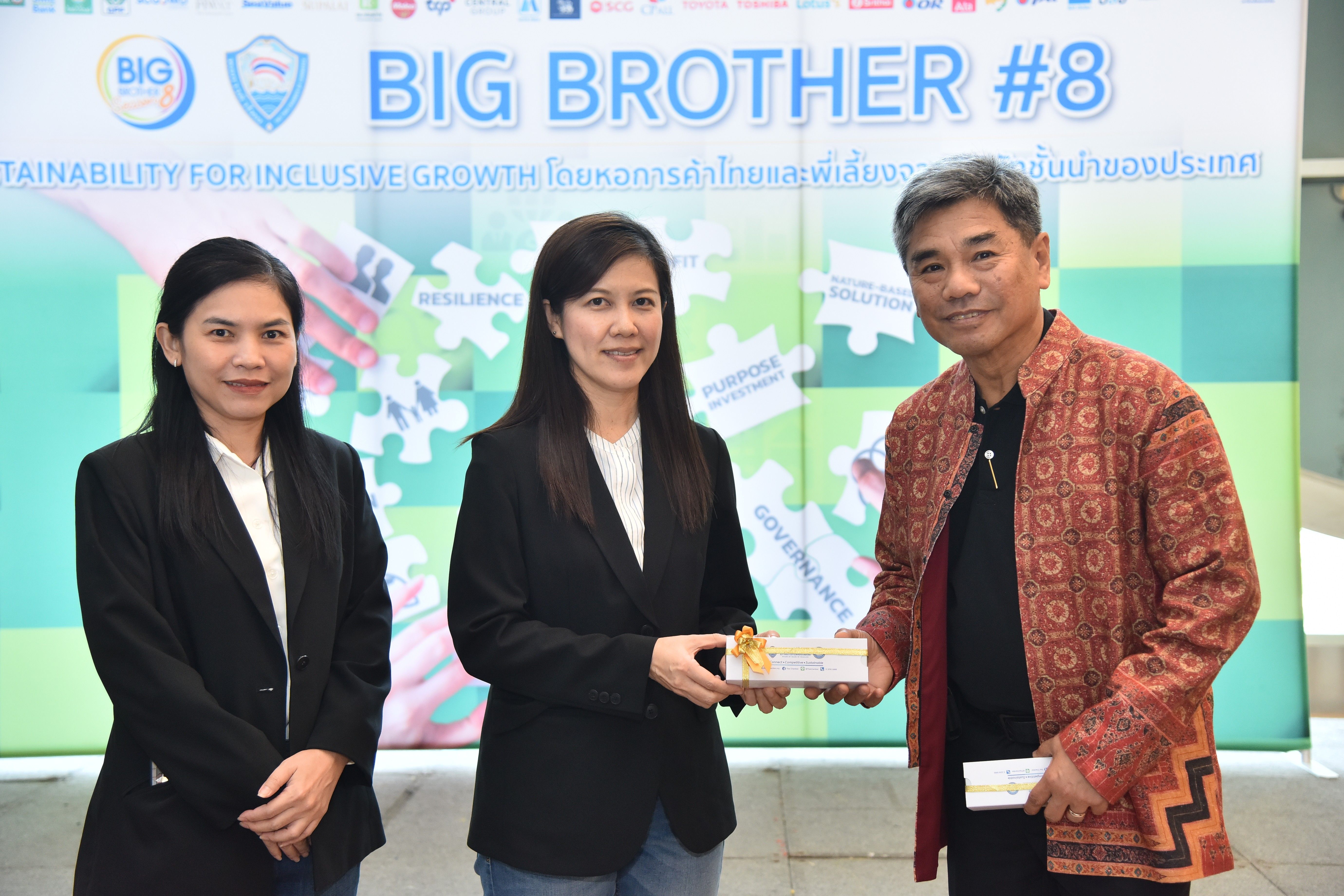 Man presents an award to a woman at the "BIG BROTHER #8" event, observed by another woman.