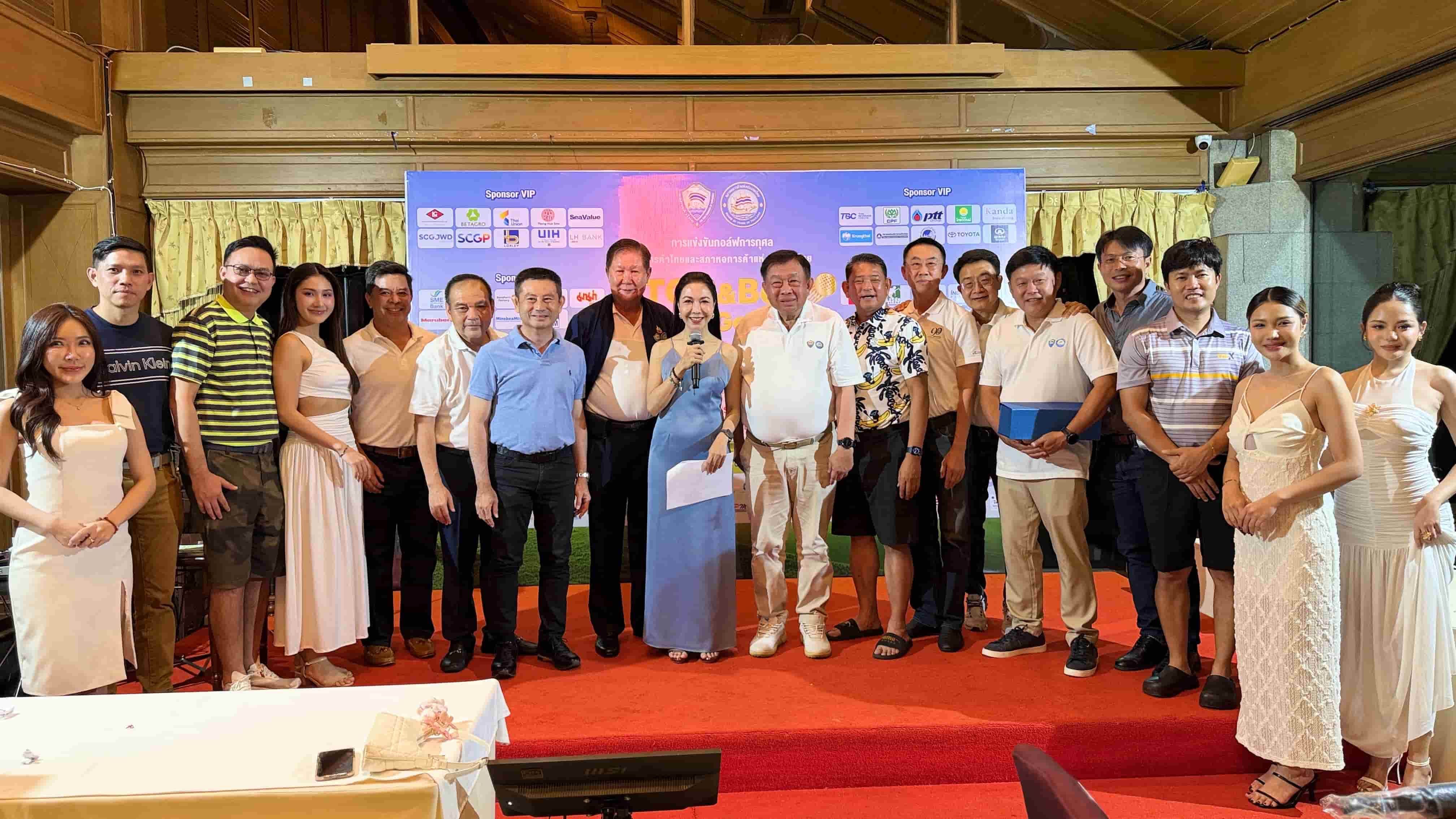 A large group of professionals poses on a red carpet in front of an event banner.