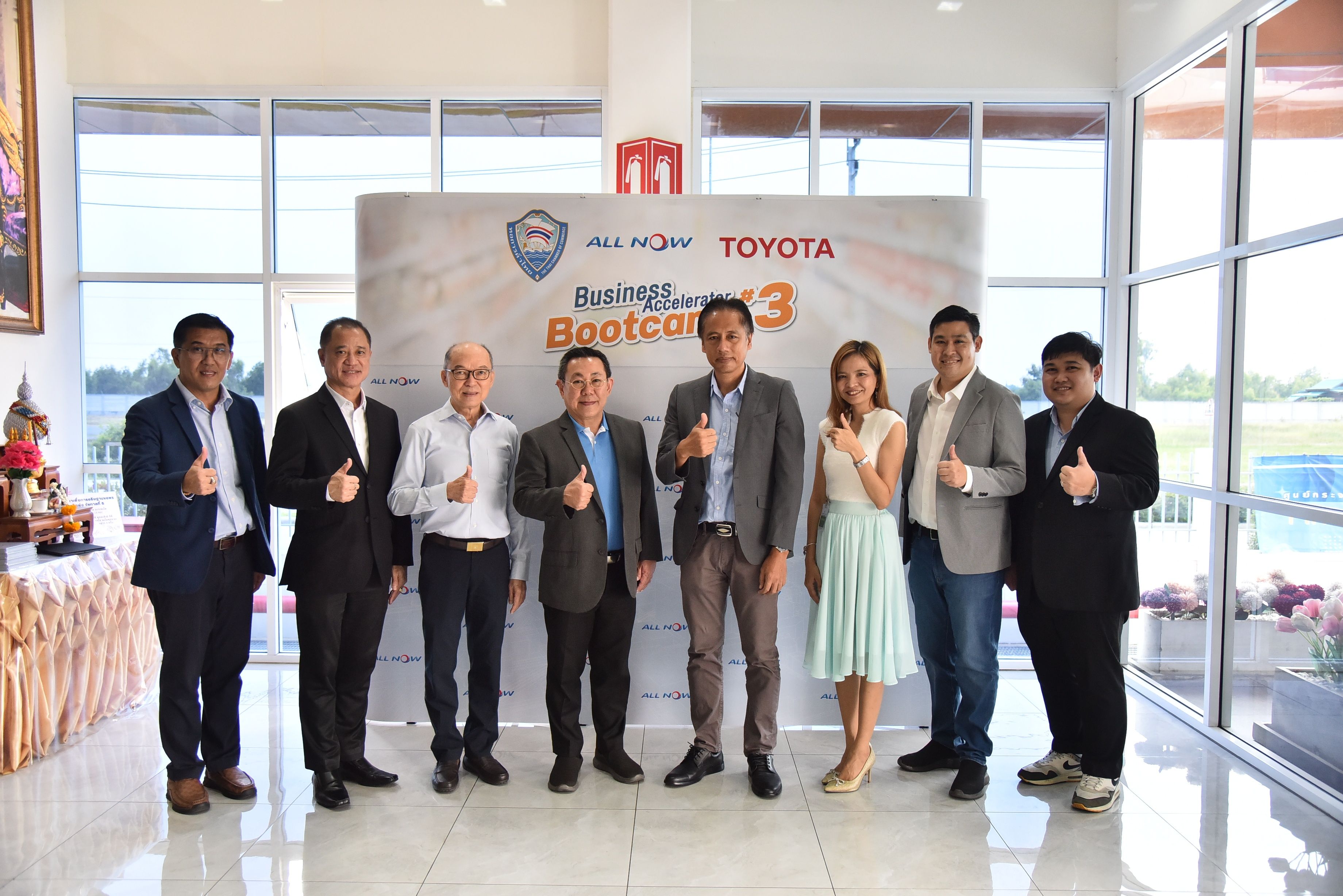 Group of eight professionals giving thumbs up in front of a Toyota Bootcamp 3 banner.