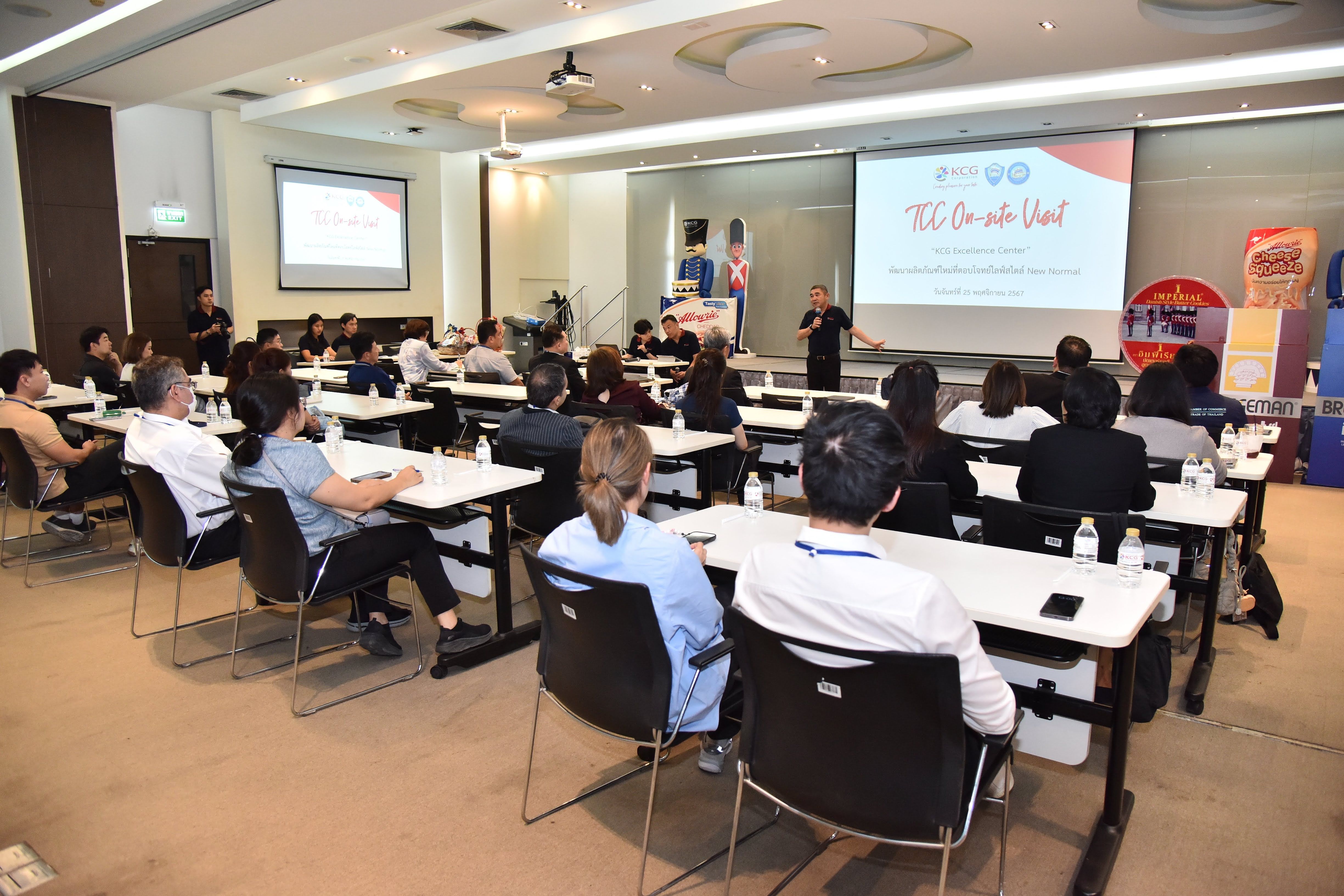 Attendees listen attentively to a speaker presenting information on a screen during a conference.