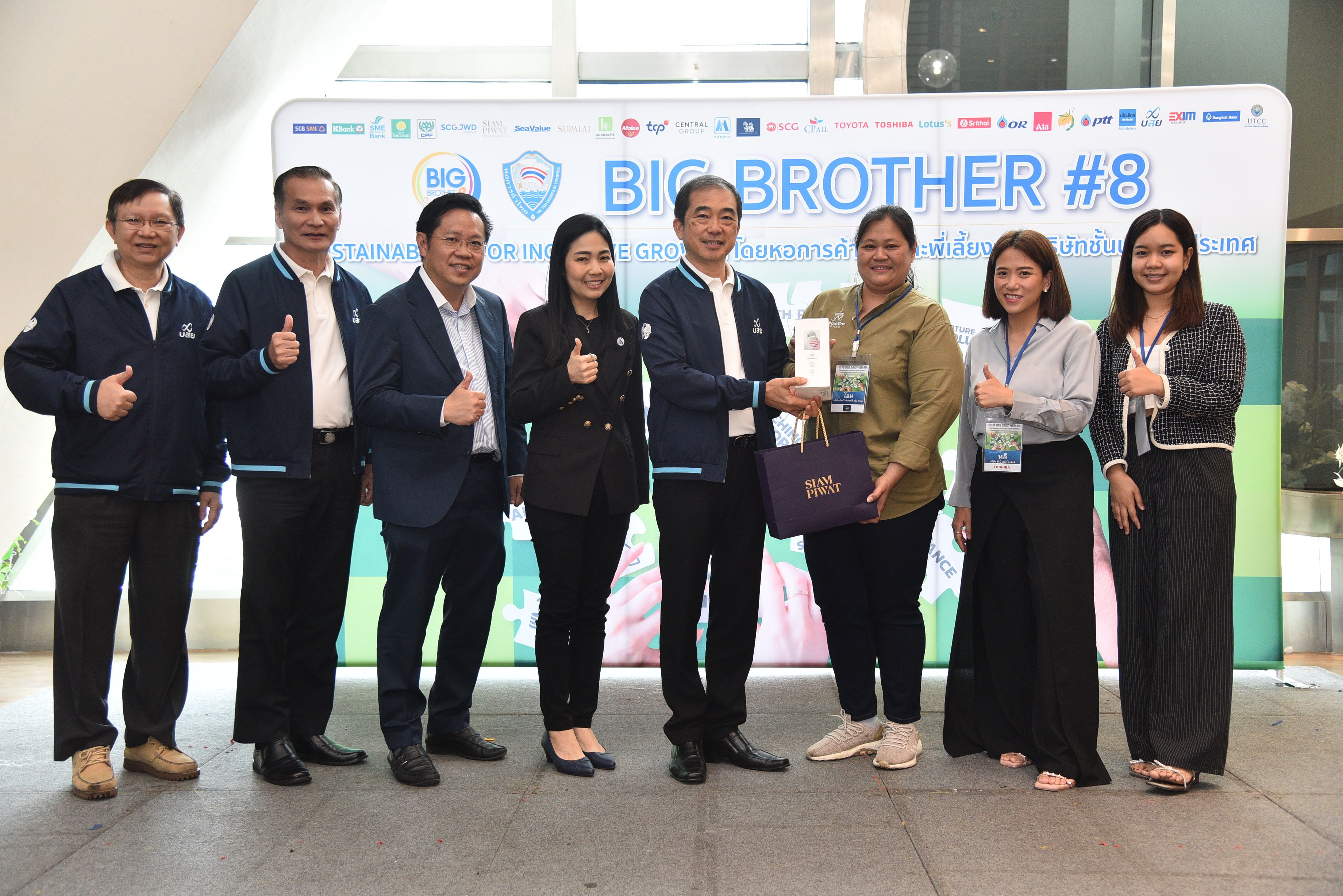Group of eight people posing with awards in front of a 'BIG BROTHER #8' banner.
