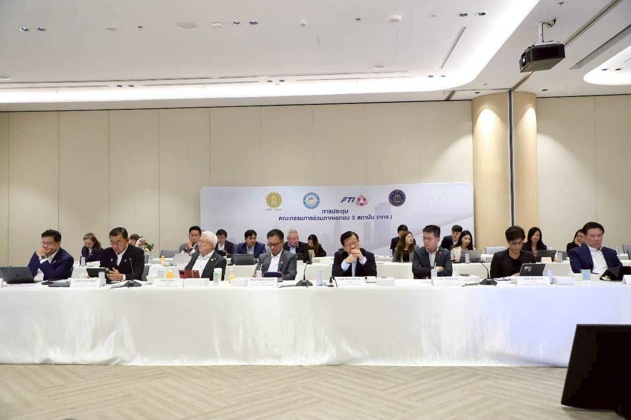 Professionals attend a formal meeting at a long conference table with a banner.