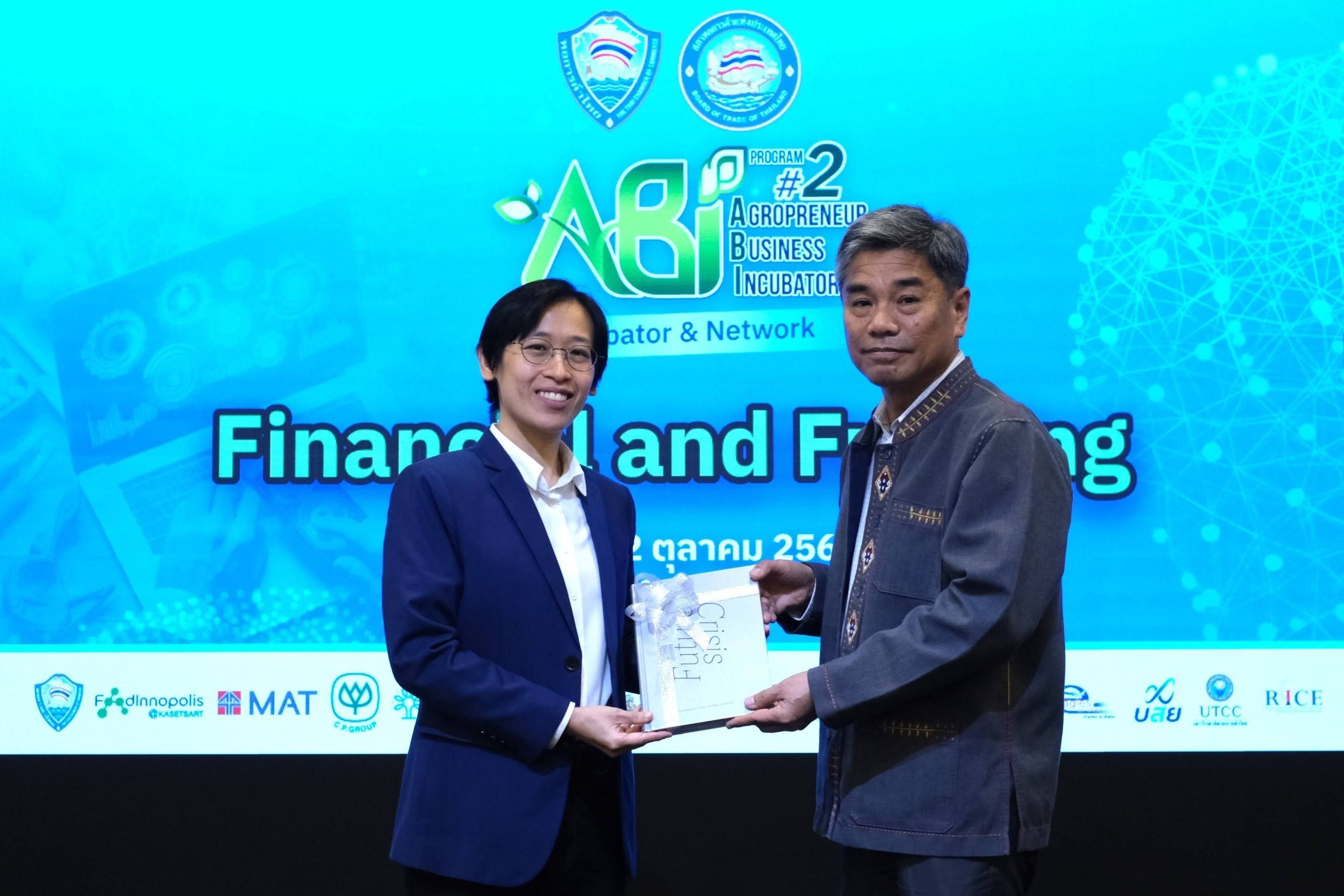 Two professionals on stage present a clear award during a "Finance and Funding" event.