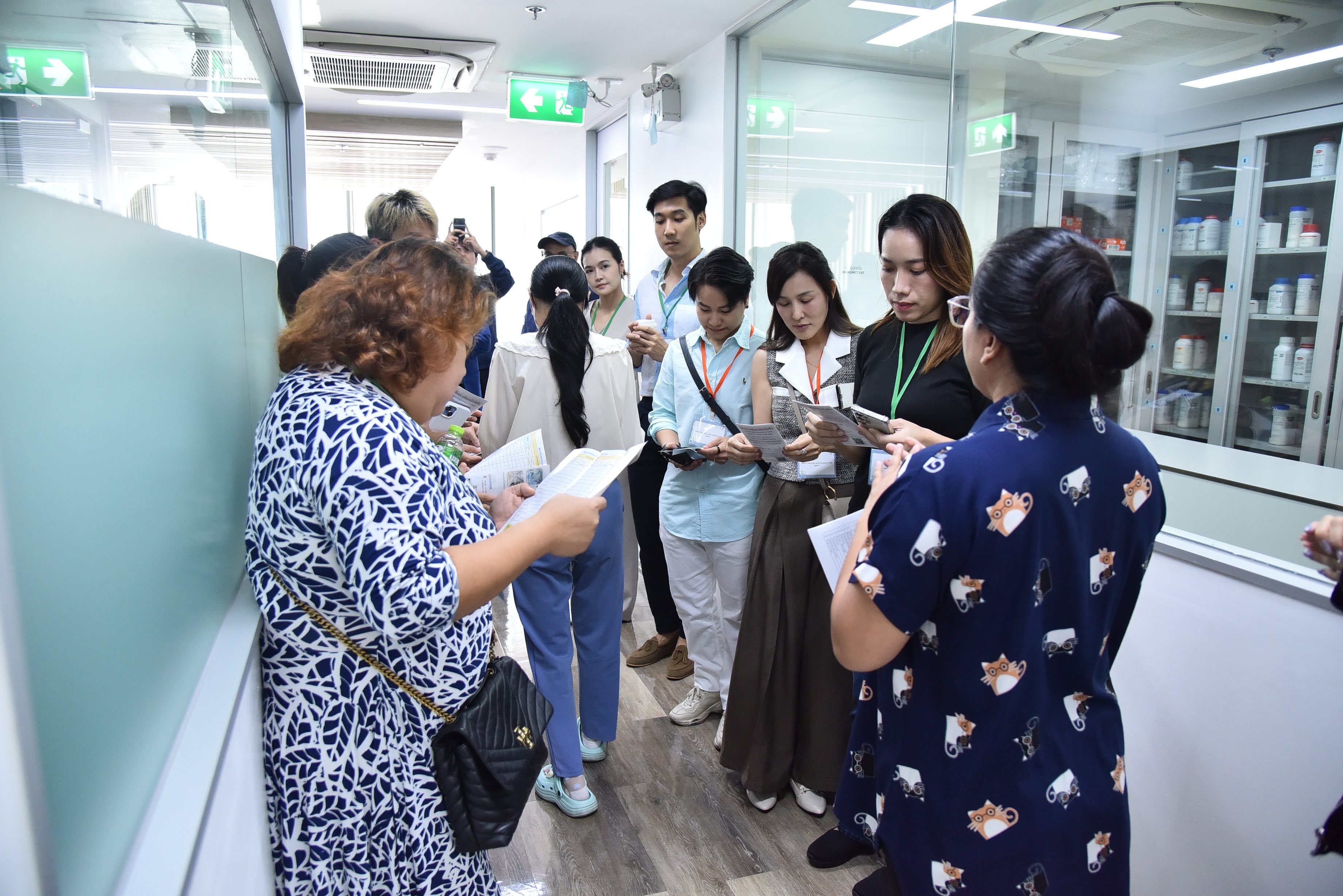 Diverse group of people reading papers in a bright, modern hallway.