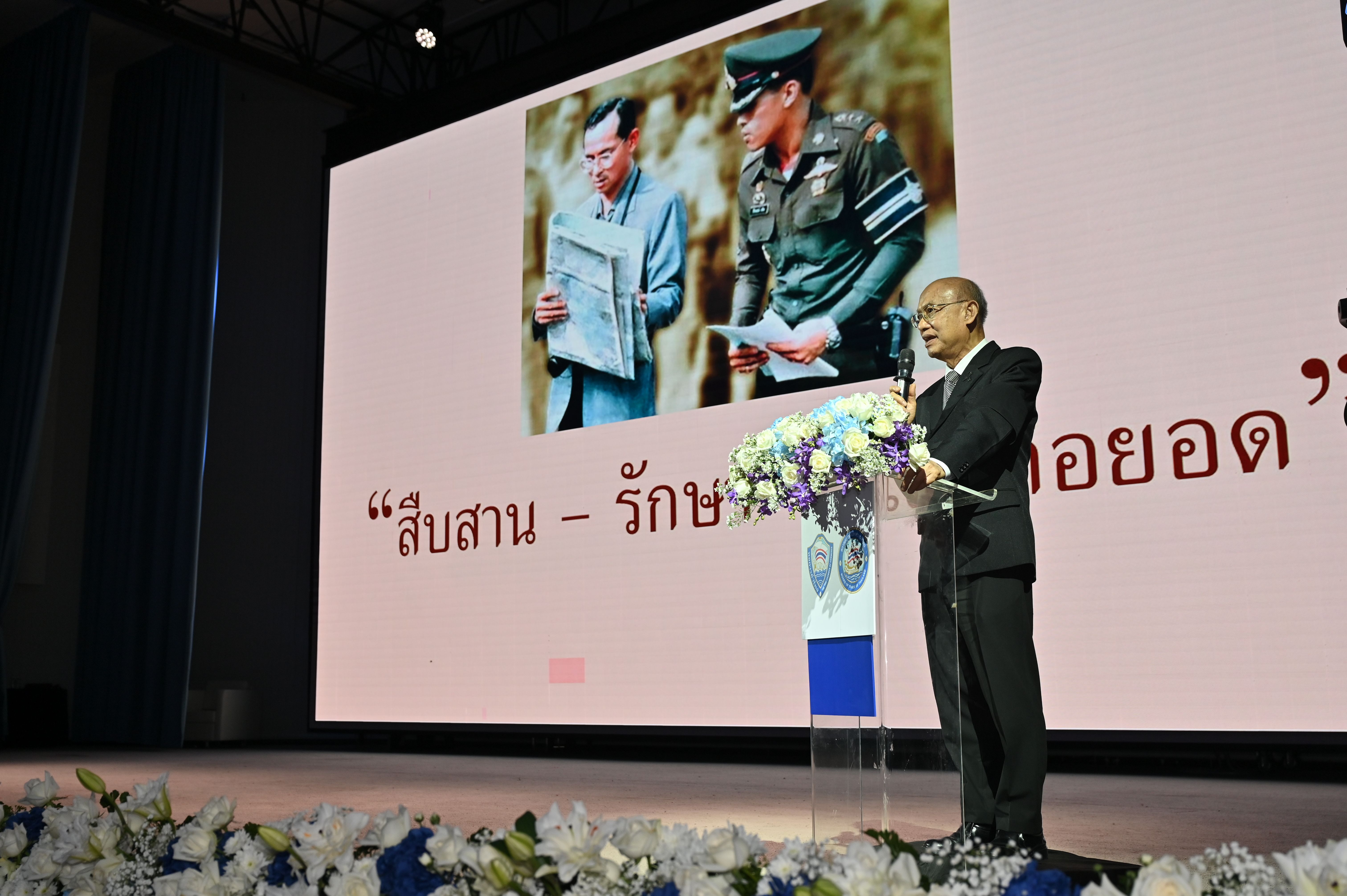 Man presenting on stage with a screen displaying a vintage photo of two men.