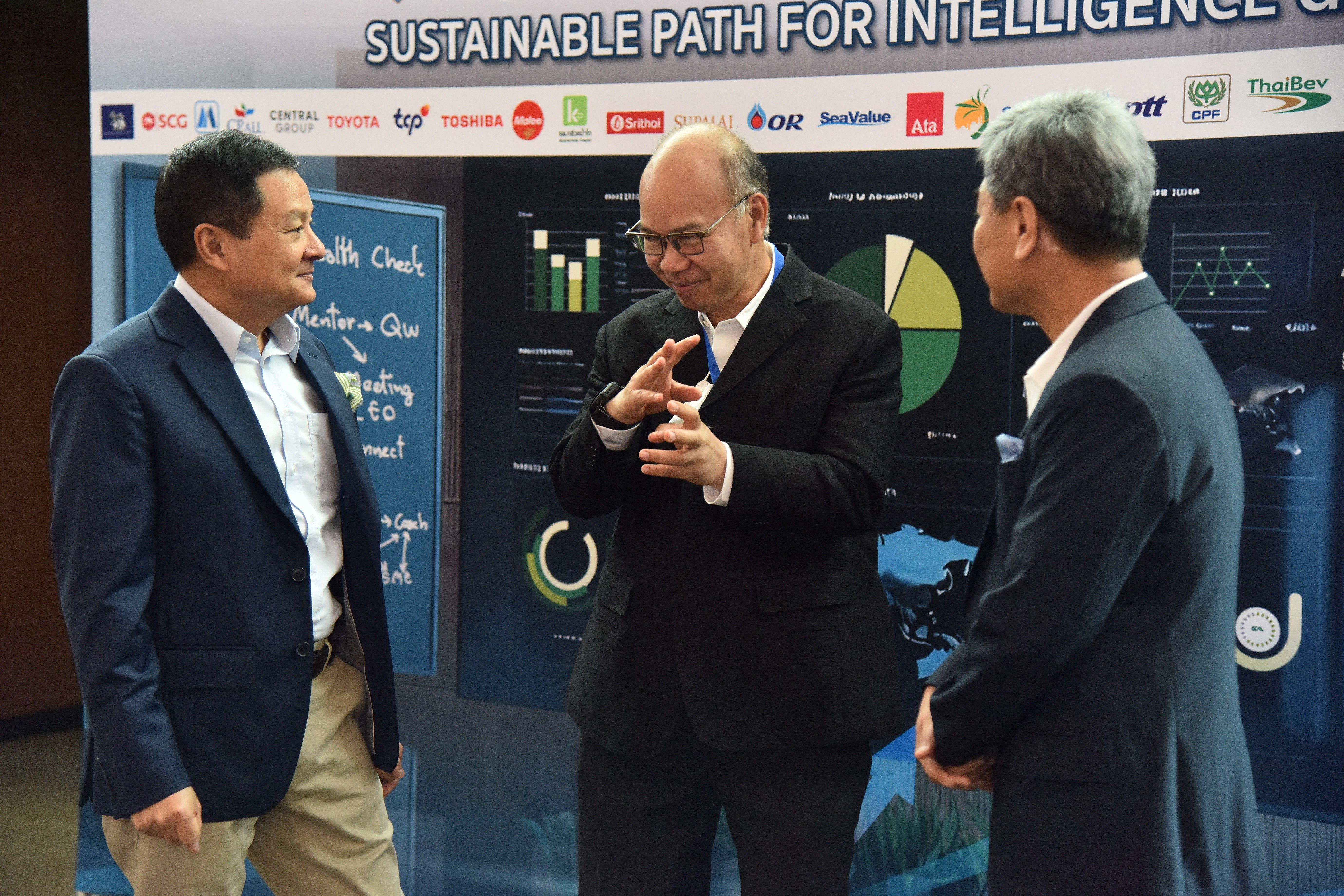 Three businessmen discuss data visualization charts on a large digital display at a conference.