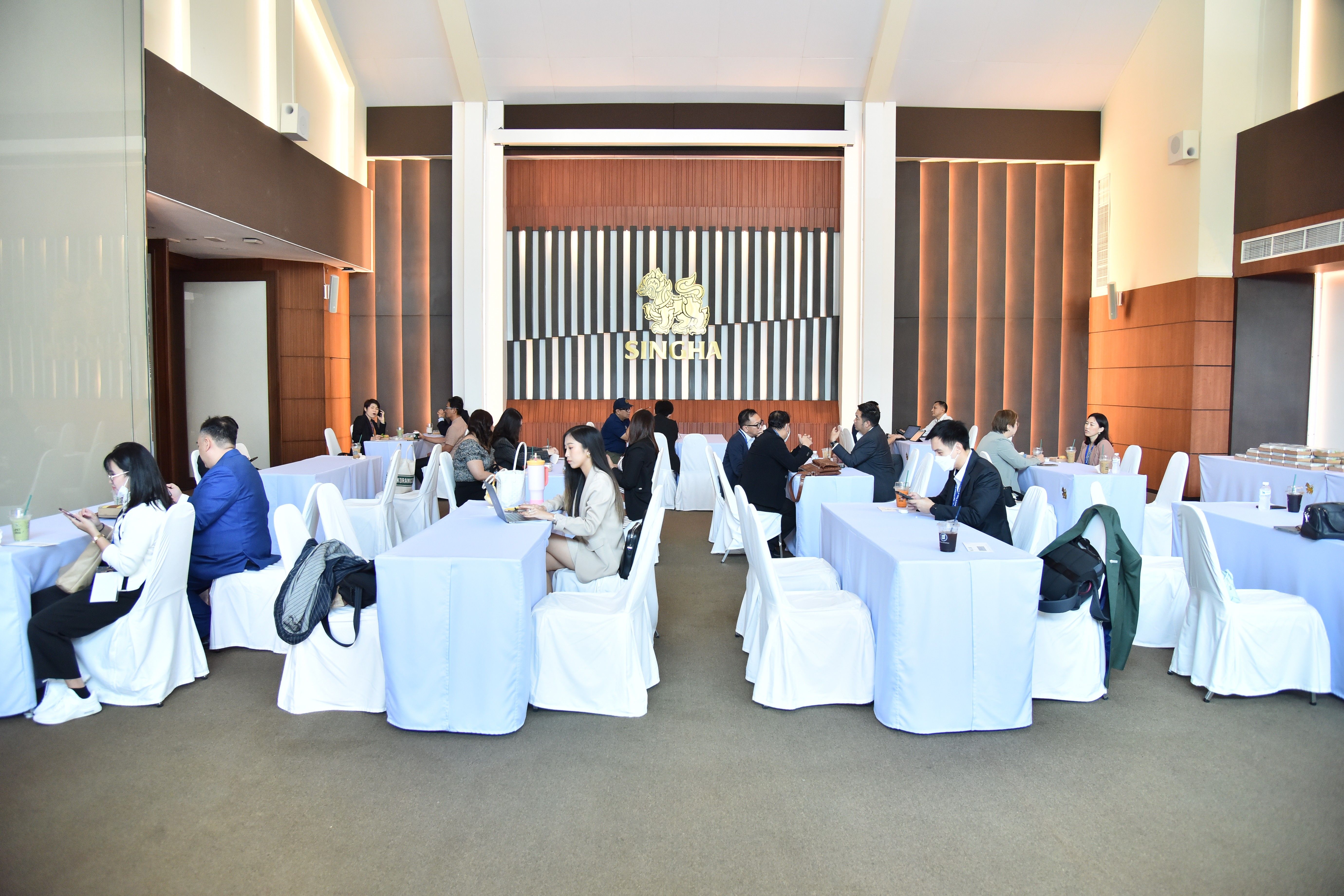 People attending a meeting in a spacious conference room with long tables.