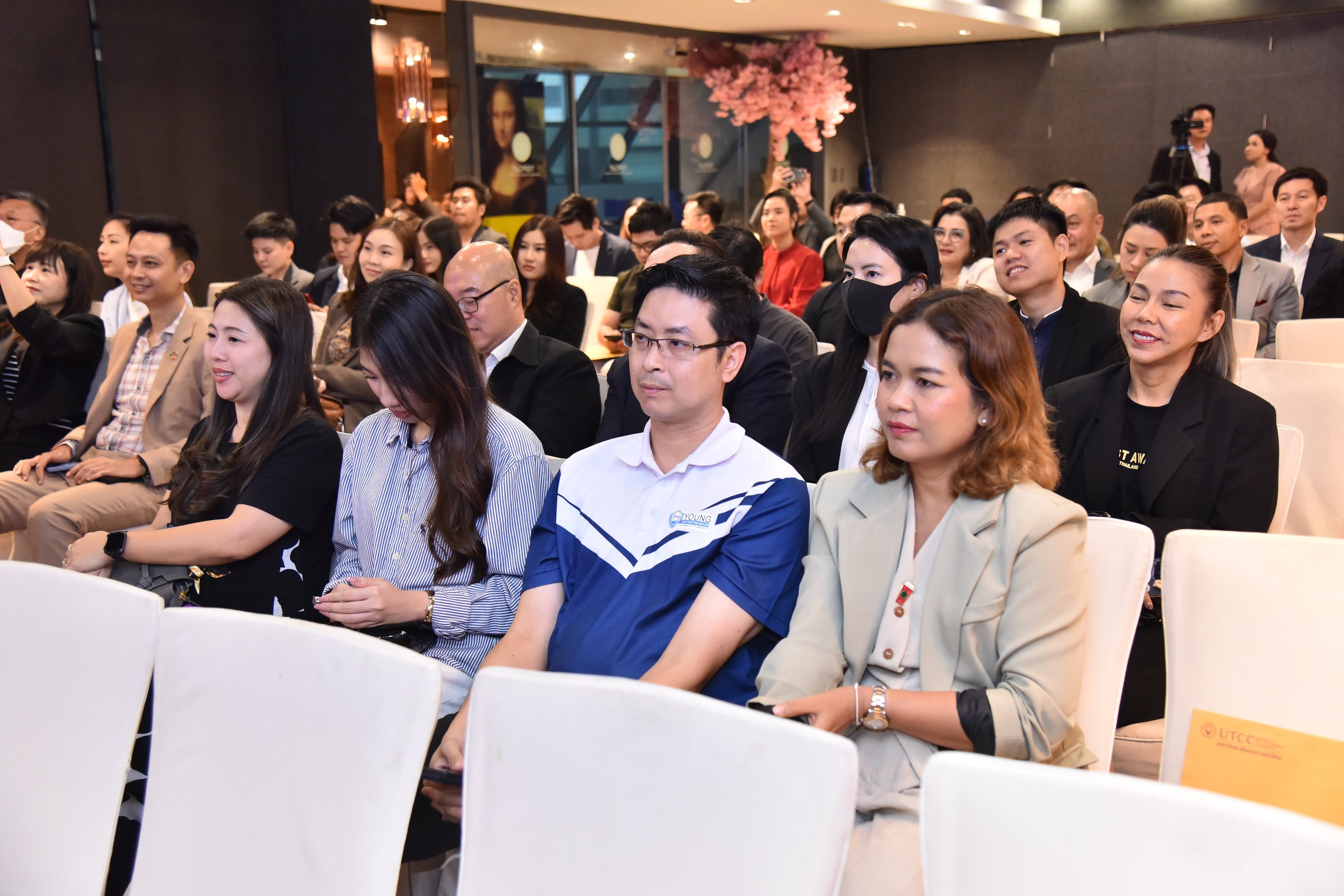 A diverse group of attendees seated, attentively watching an event in a professional setting.