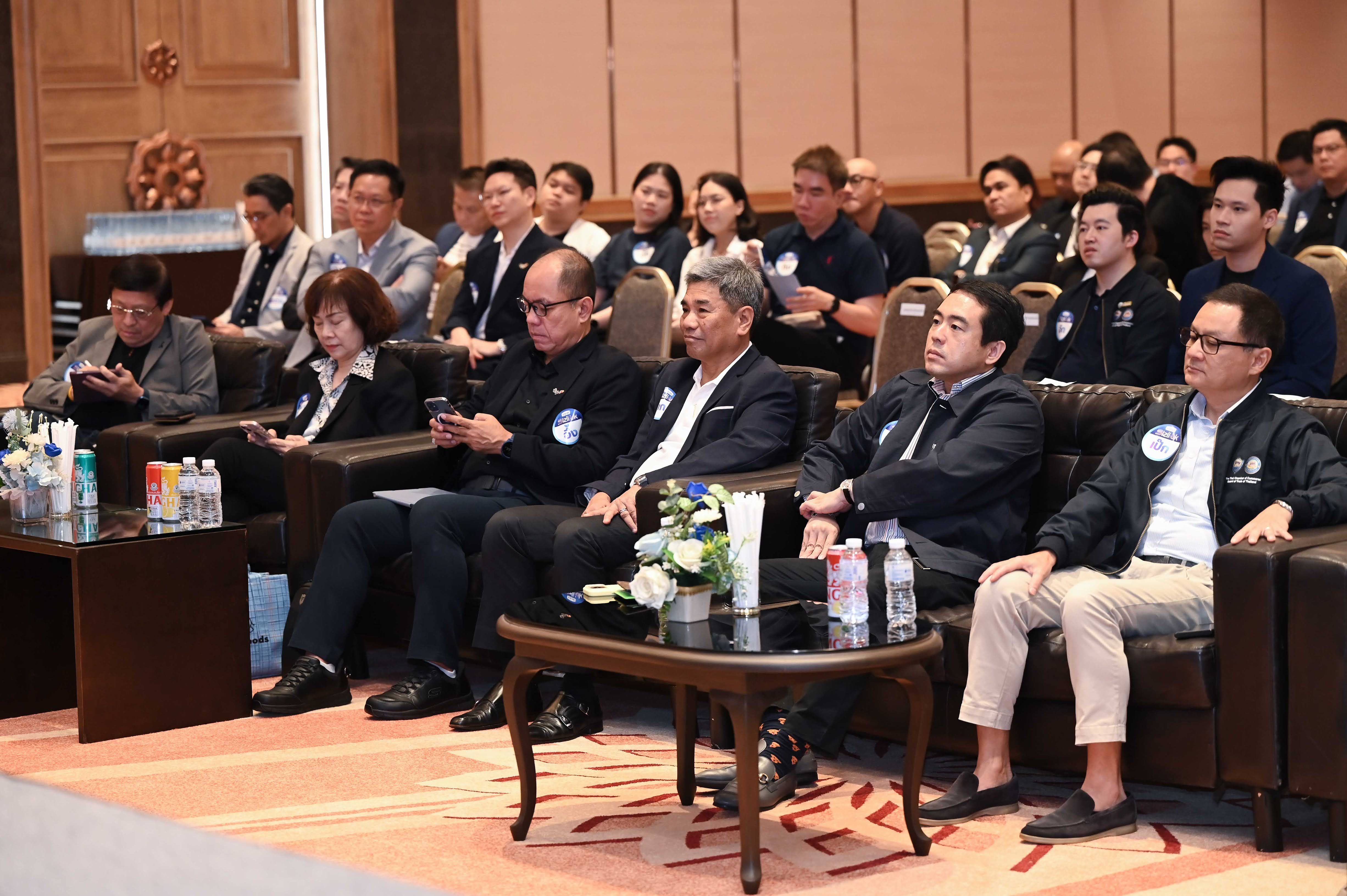 Professionals attend a conference, seated in rows, listening attentively in a modern meeting room.