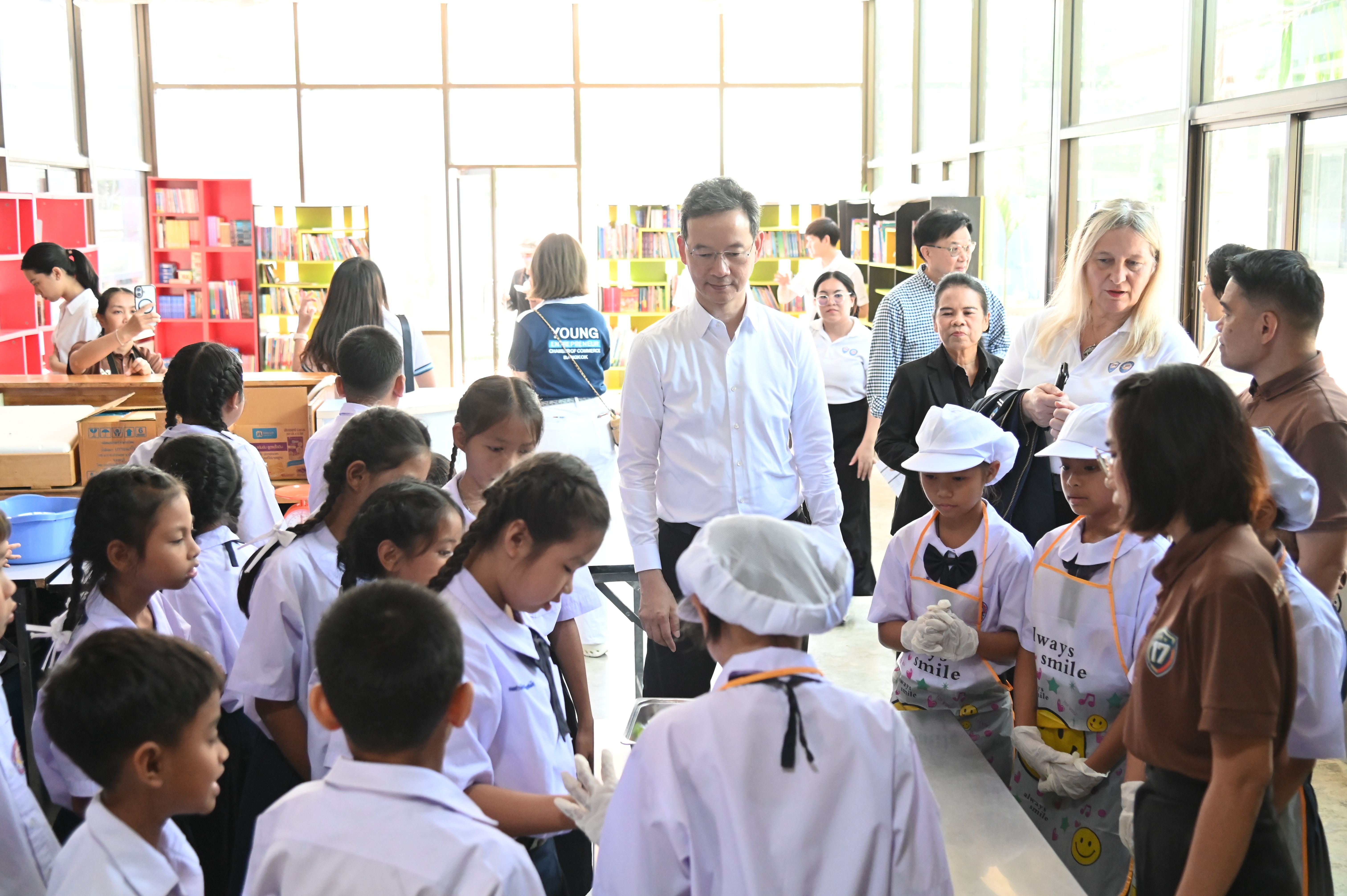 Adults interact with children in school and chef uniforms during an indoor event.