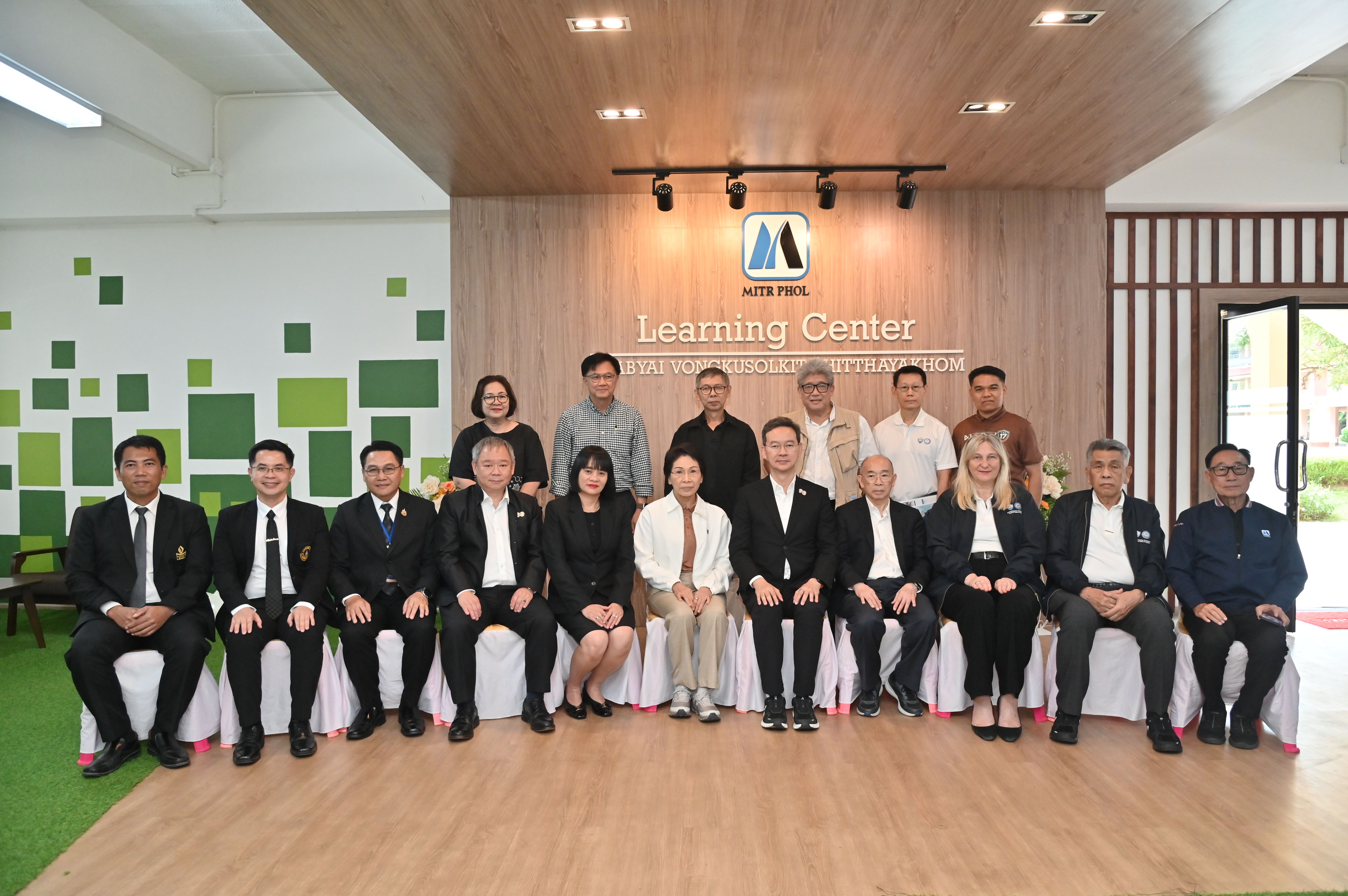Group of business professionals posing in front of a sign for a Learning Center.