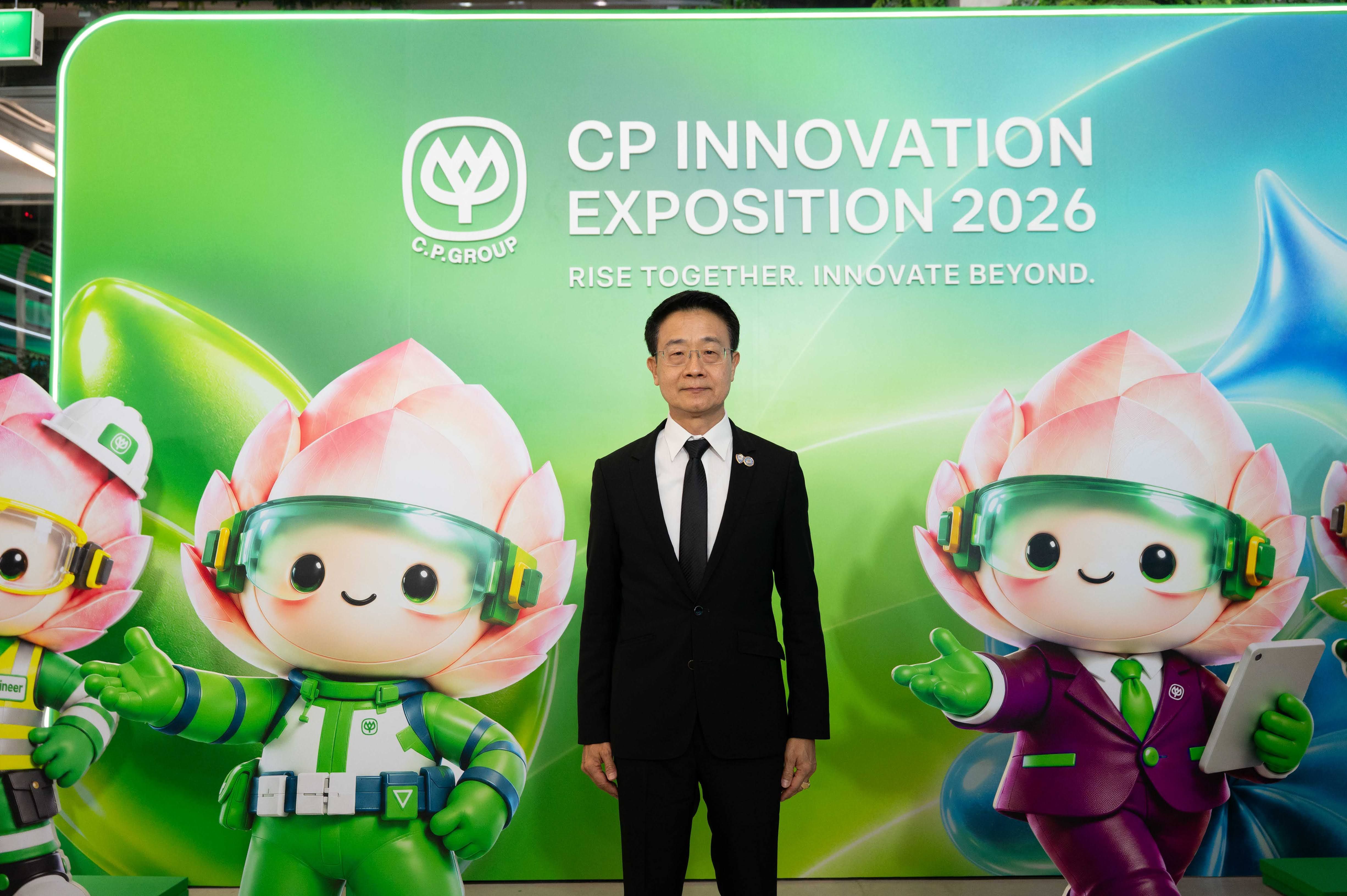 Man in a suit with flower mascots at the CP Innovation Exposition 2026 banner.