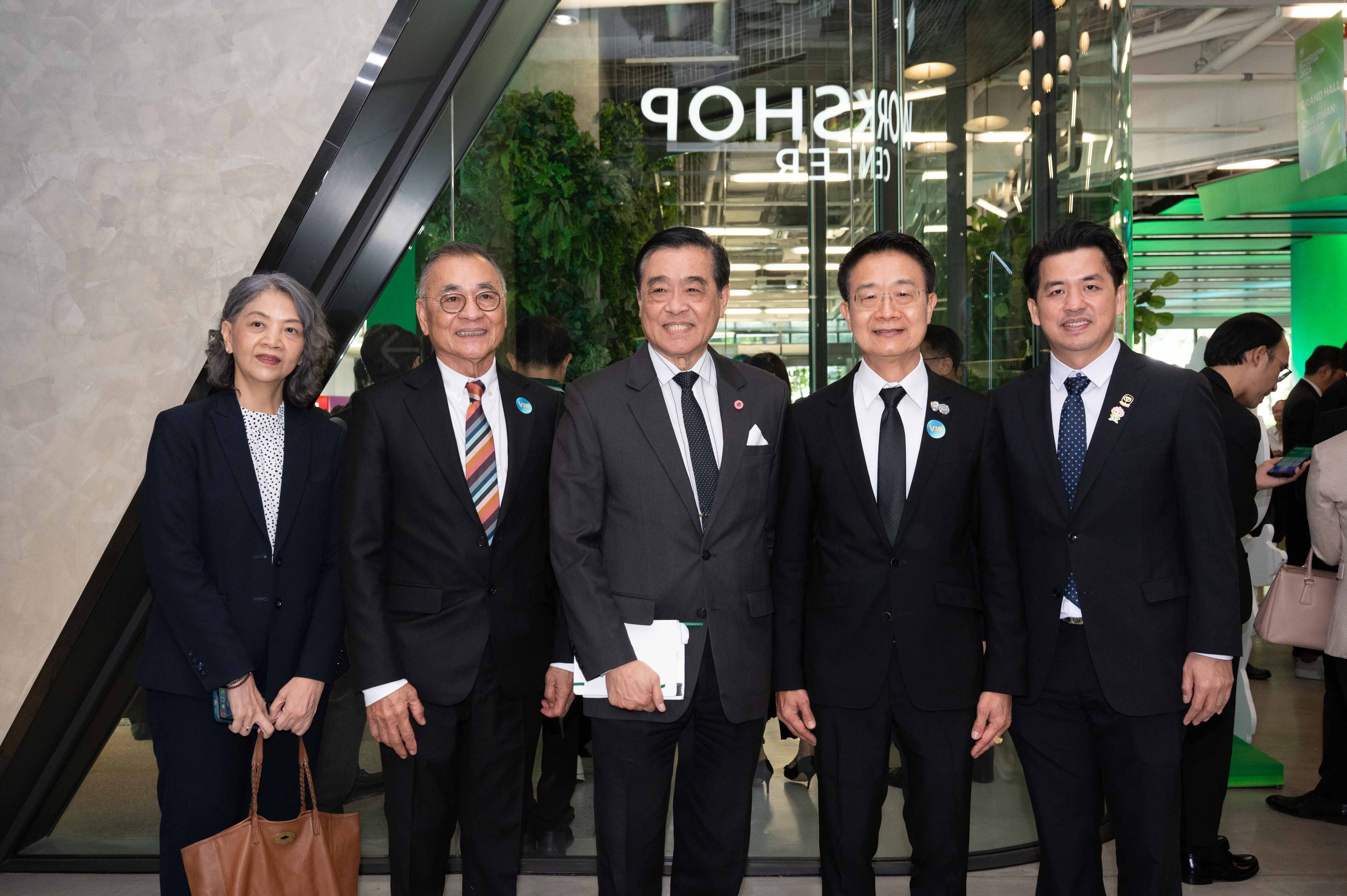 Five professionals, three men and two women, pose formally inside a modern building.