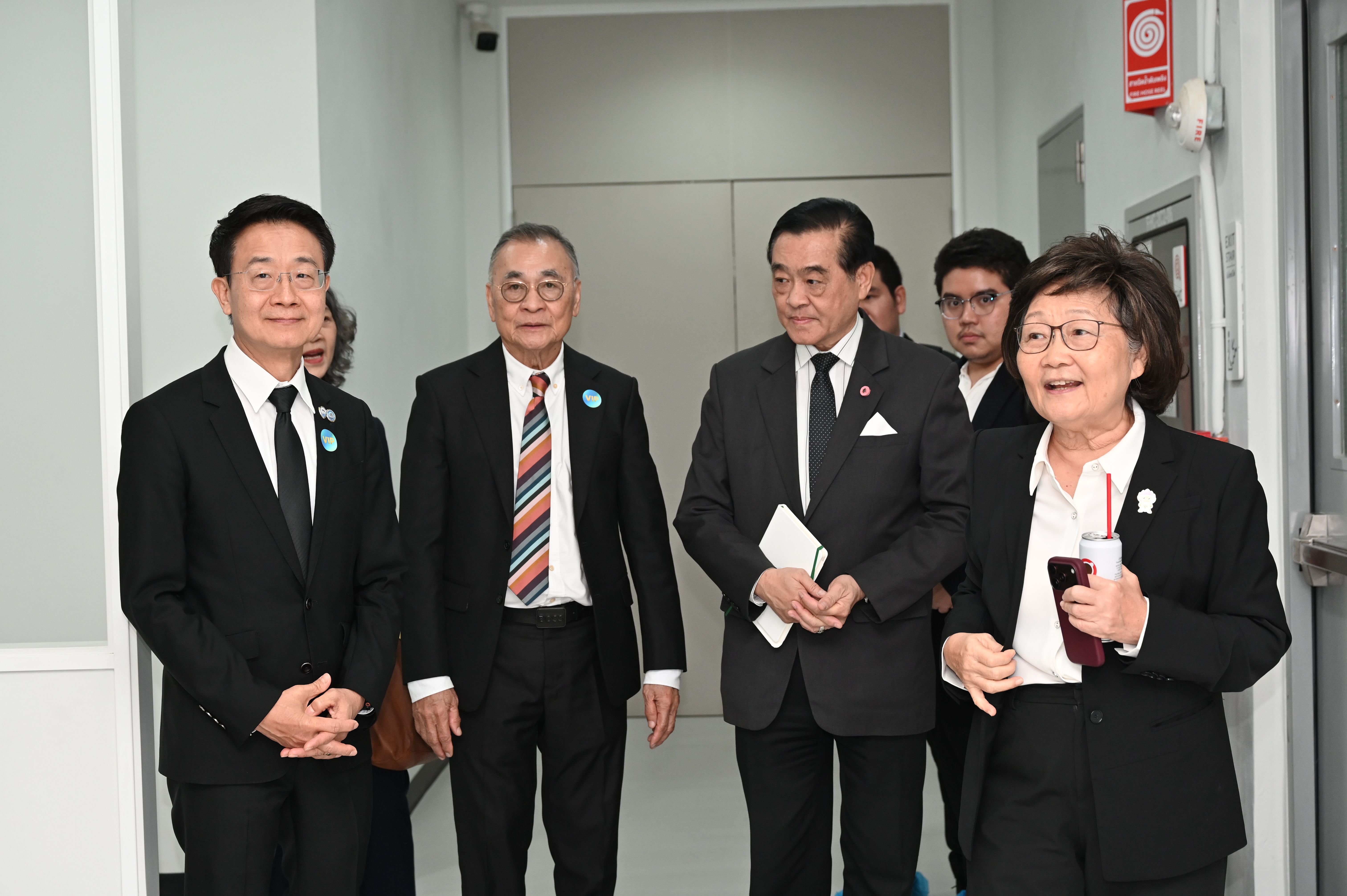 Five professionals, including a smiling woman, walk together in a modern office corridor.