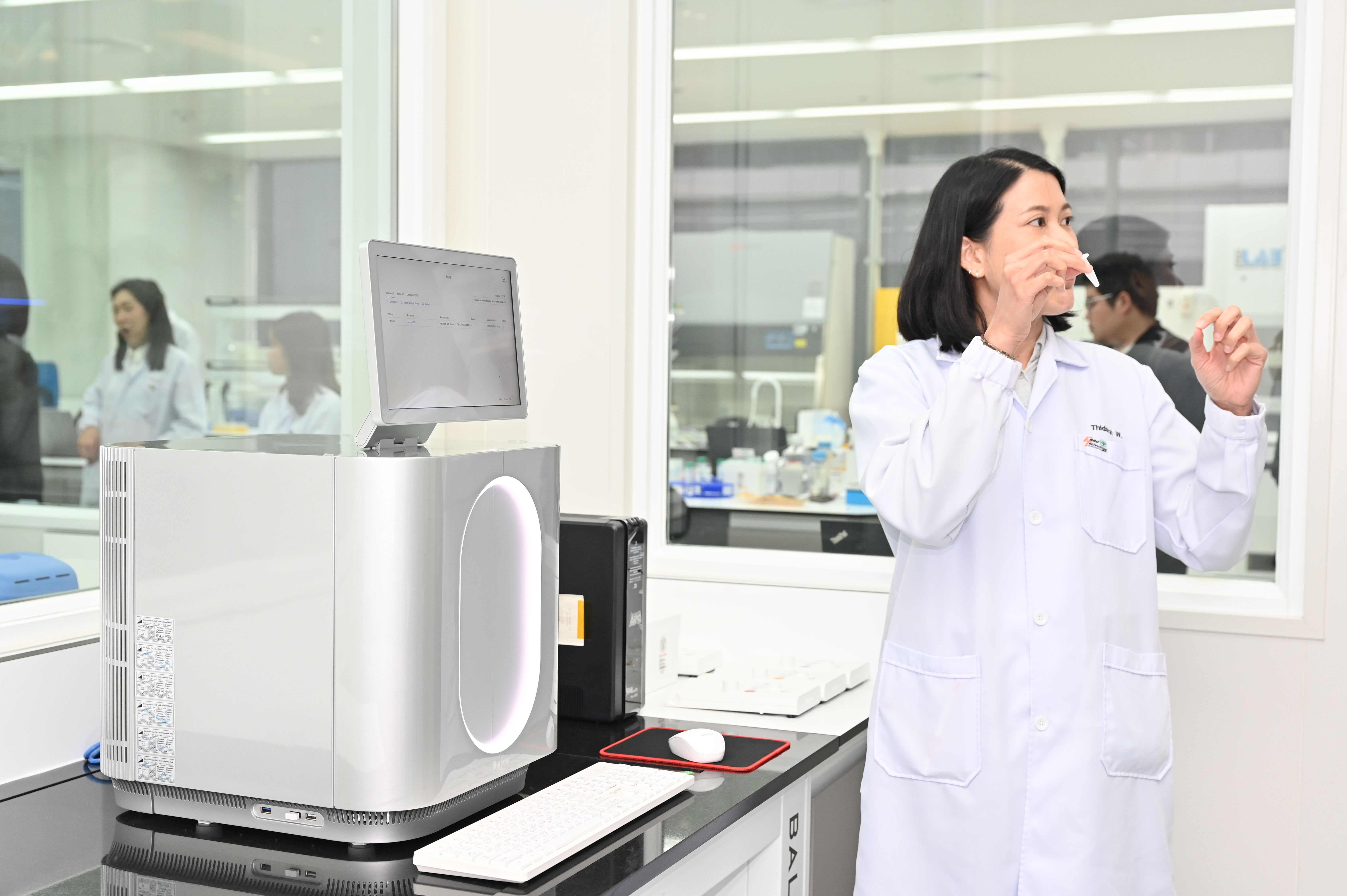 A female scientist in a lab coat examines a sample in a clean laboratory.
