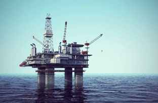 An offshore oil drilling platform standing prominently in the middle of a calm blue ocean.