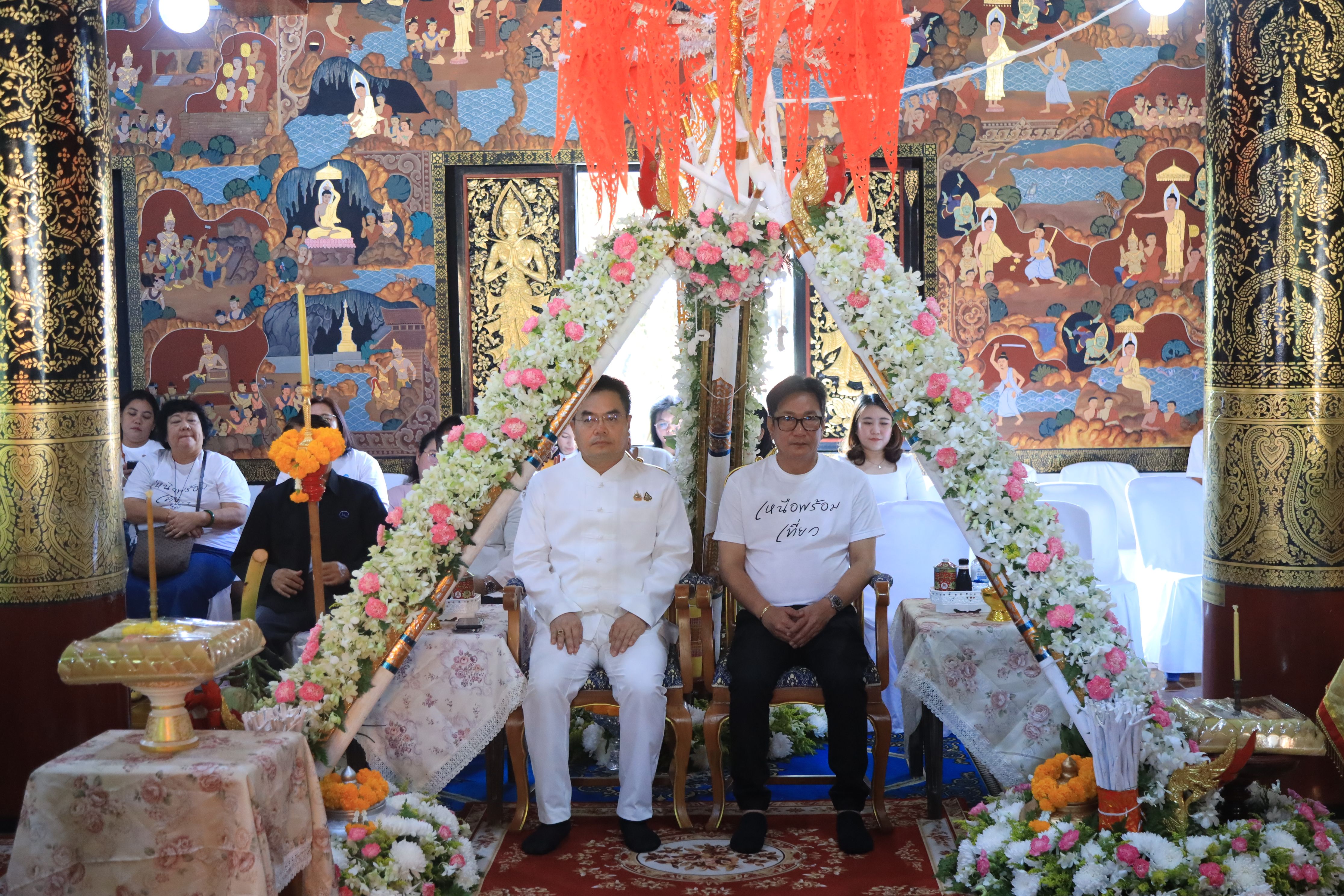 Two men seated under an elaborate floral archway in a vibrantly painted temple.