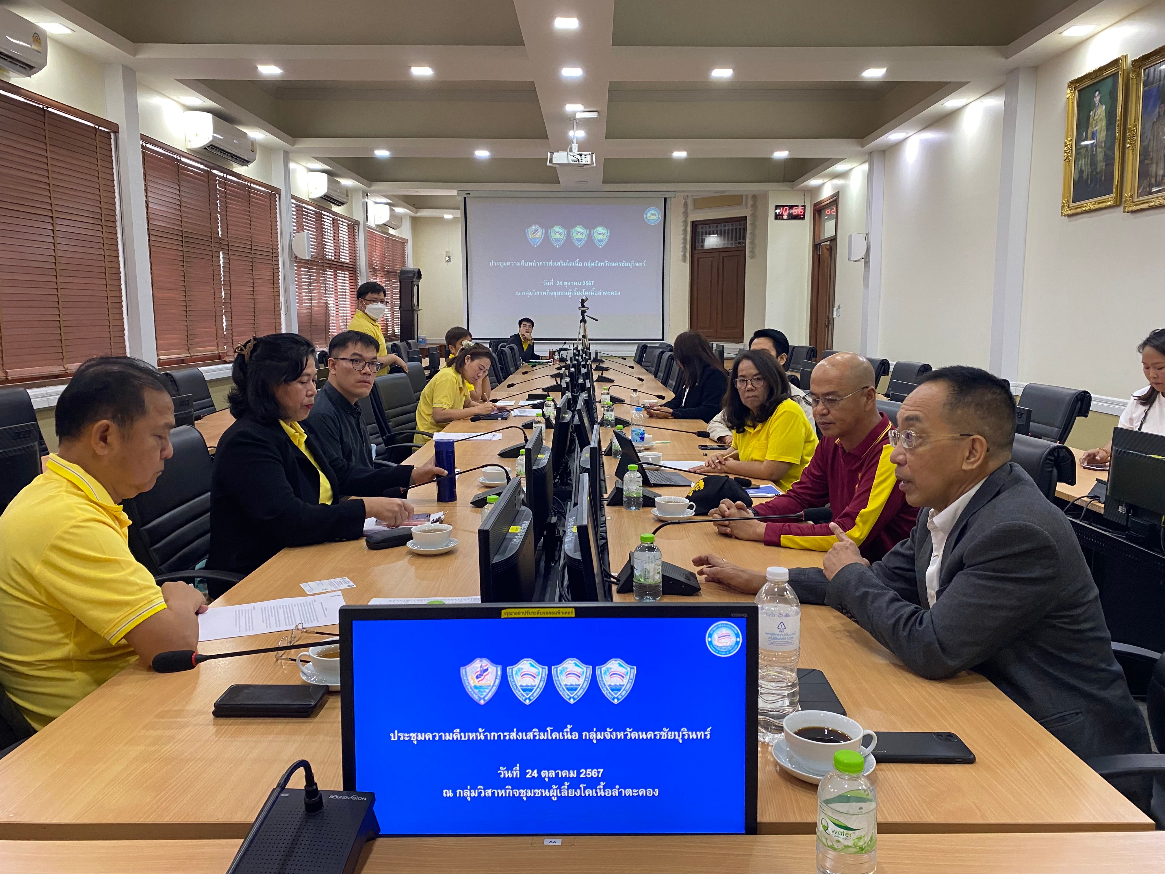Professionals in a conference room, seated around a long table during a meeting with a projector.