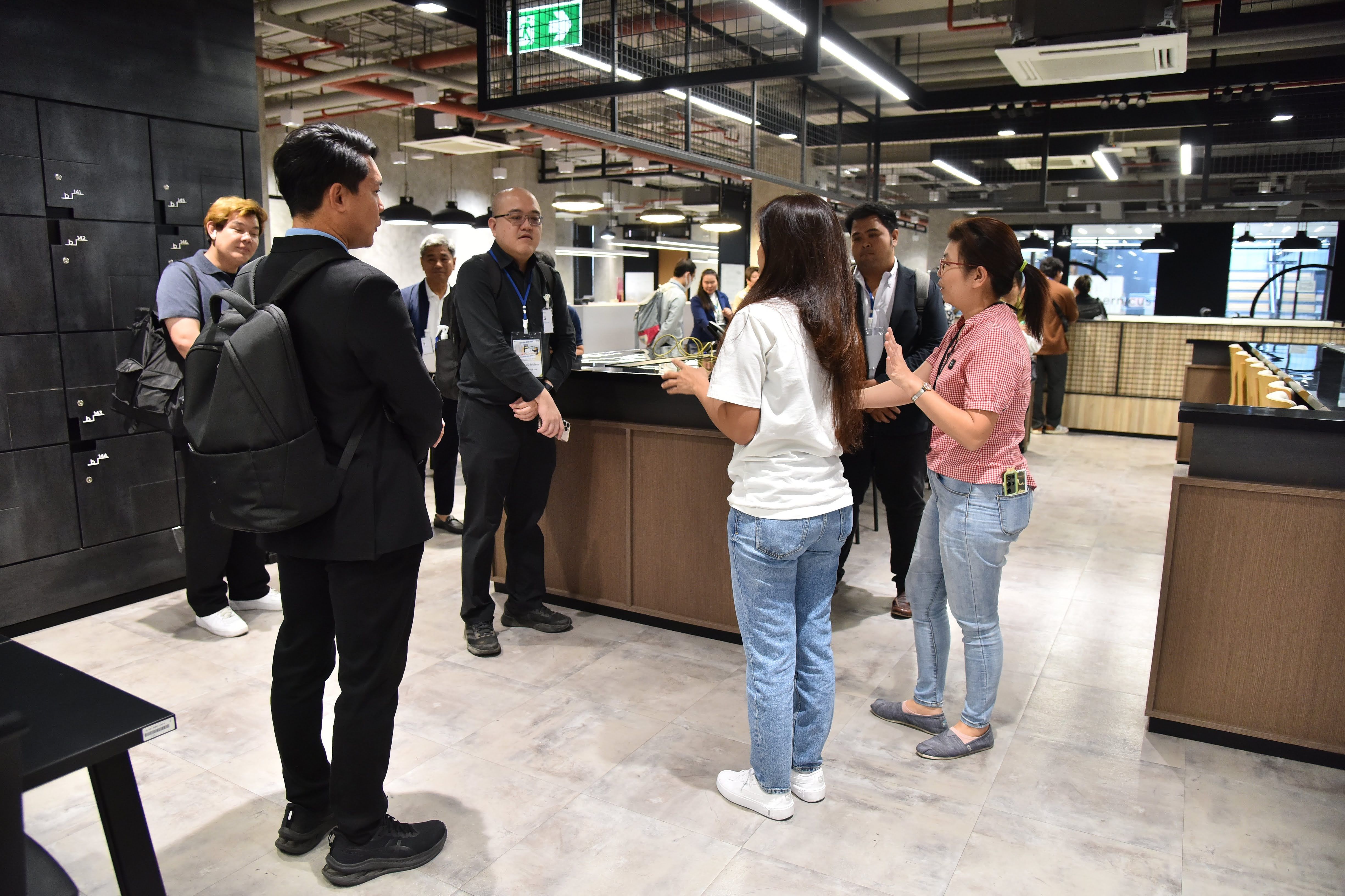 Group of young adults listening to a presenter in a modern retail showroom.