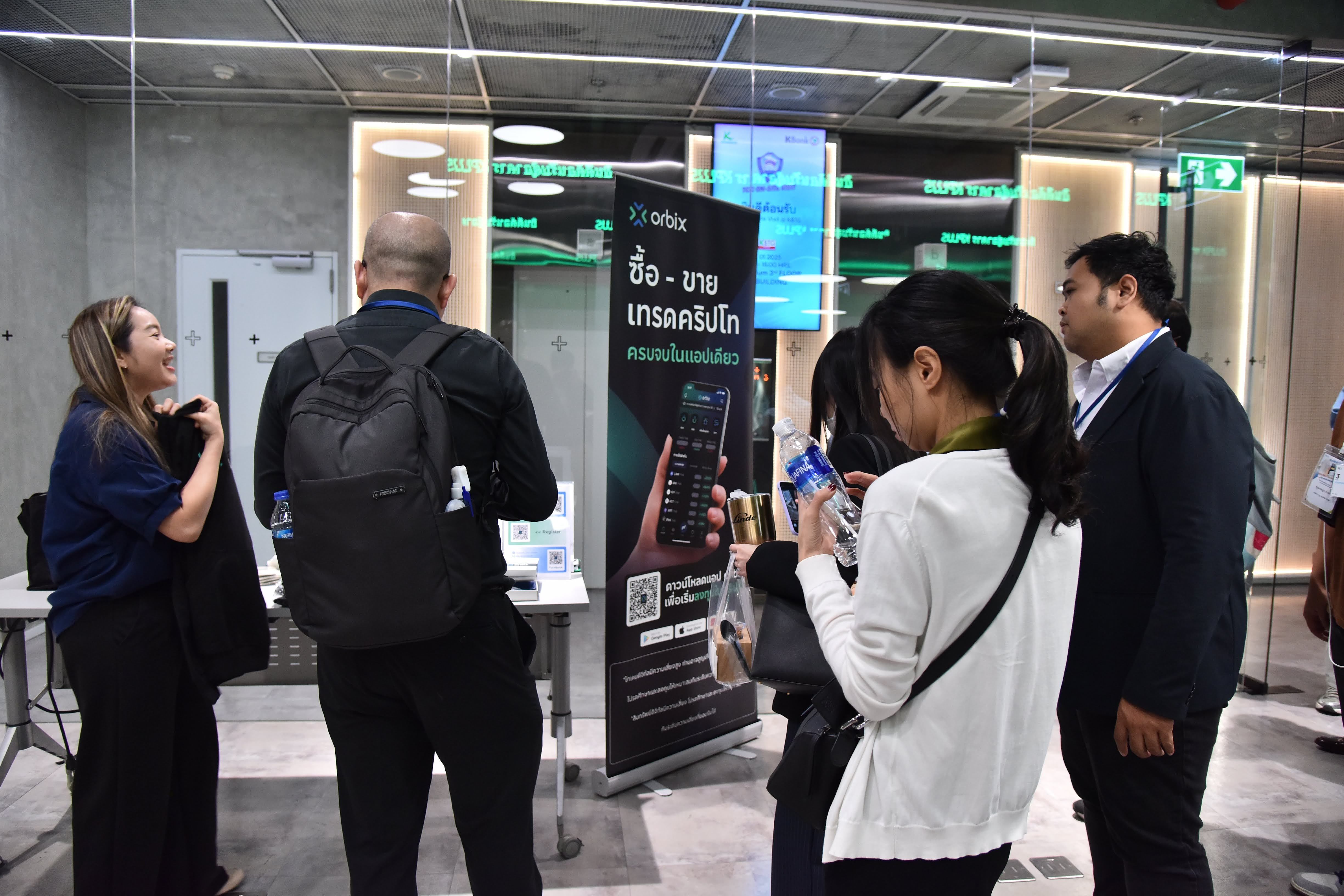 People gather around a black banner displaying text at an indoor event.