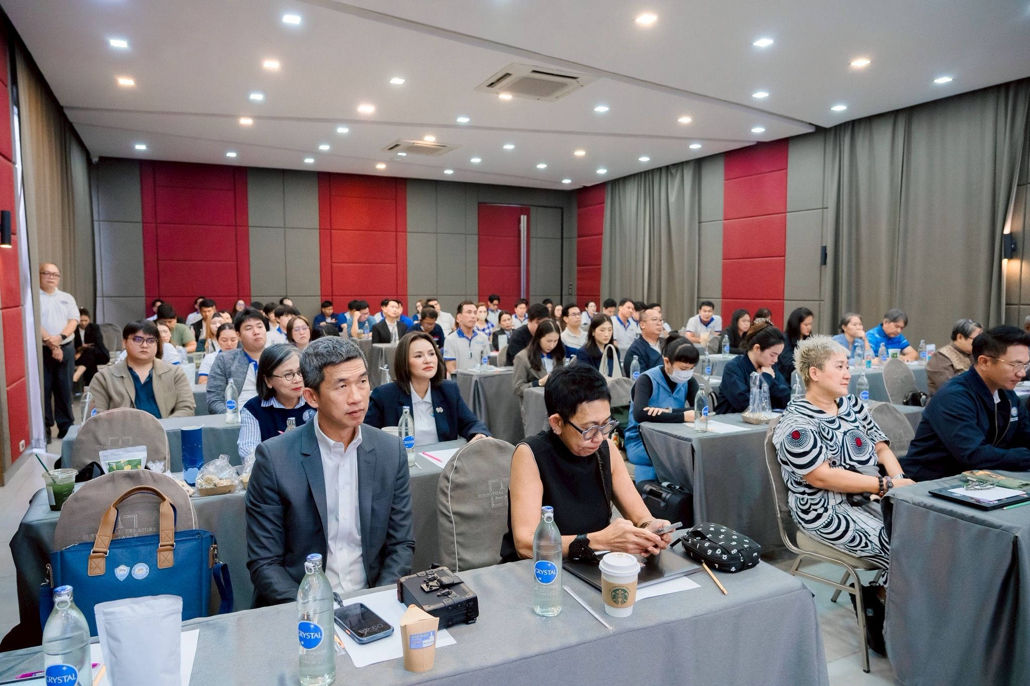 Attendees listen attentively during a professional conference or seminar in a well-lit room.