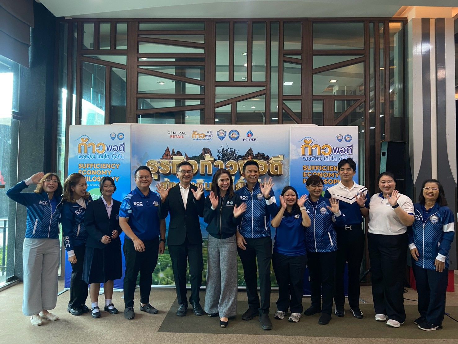 A diverse group of people smiling and posing in front of an event banner.