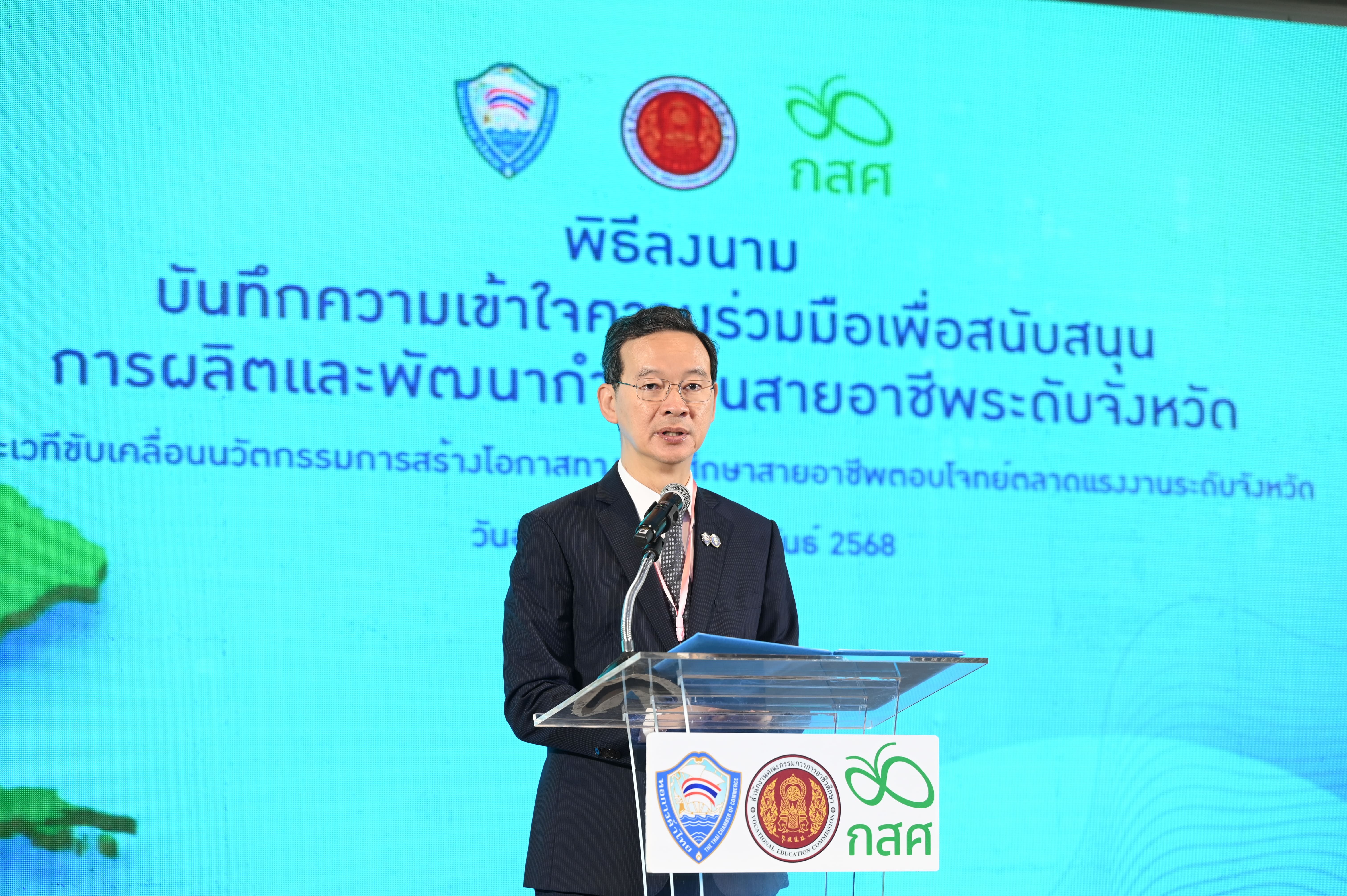 Man in suit speaks at podium during a signing ceremony for vocational development.