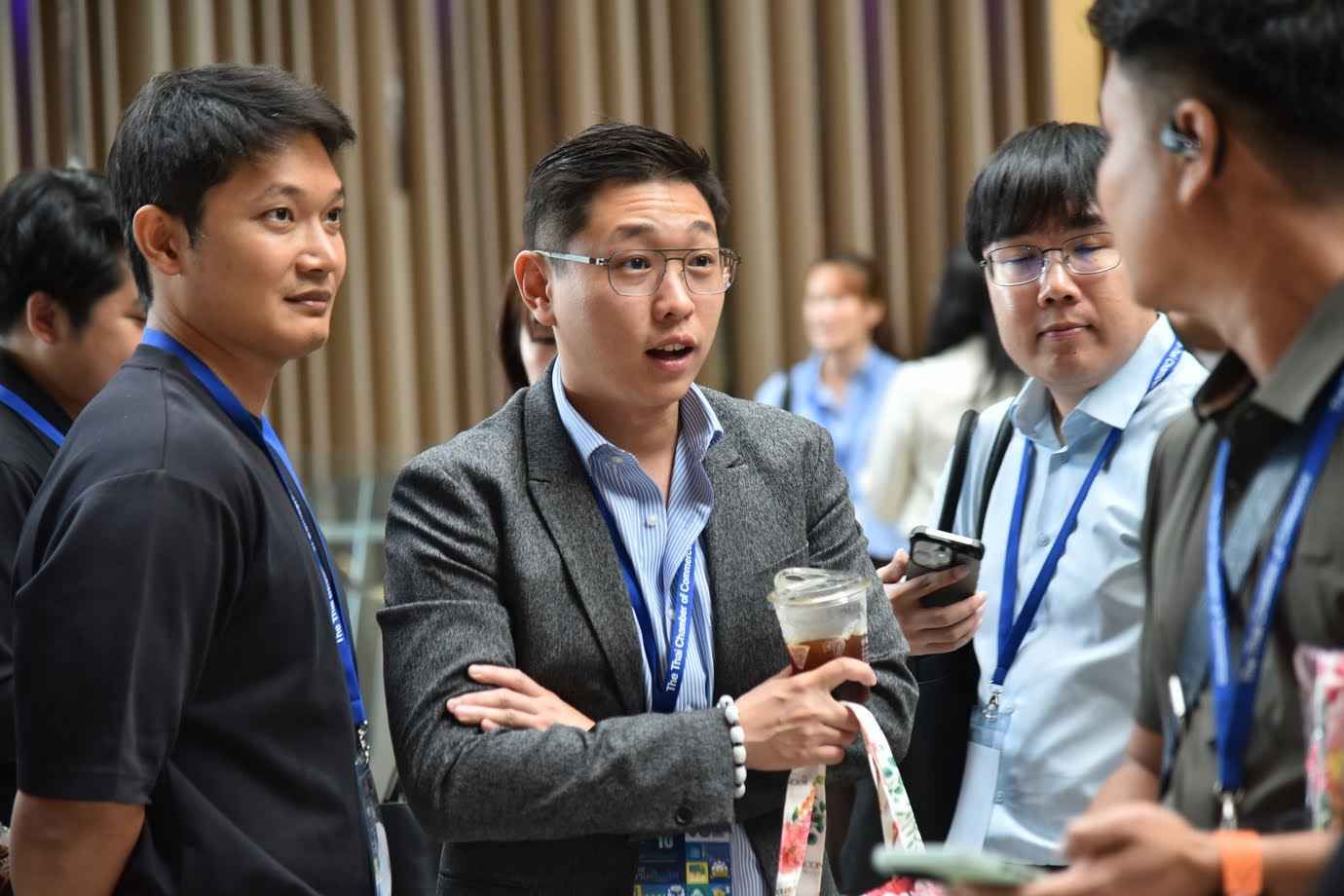 Three men engage in a lively discussion at a professional conference event.