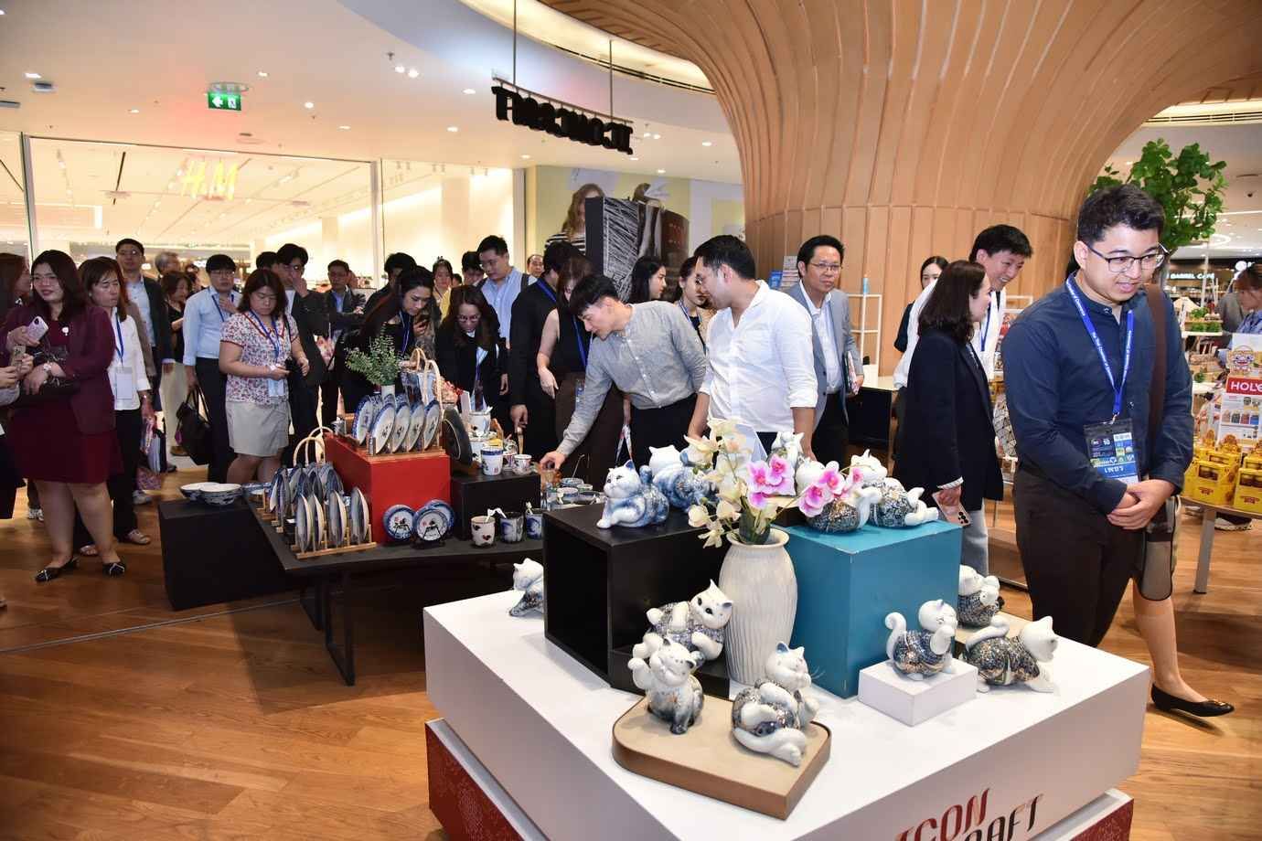People browse small decorative items on display tables in a modern, brightly lit store.