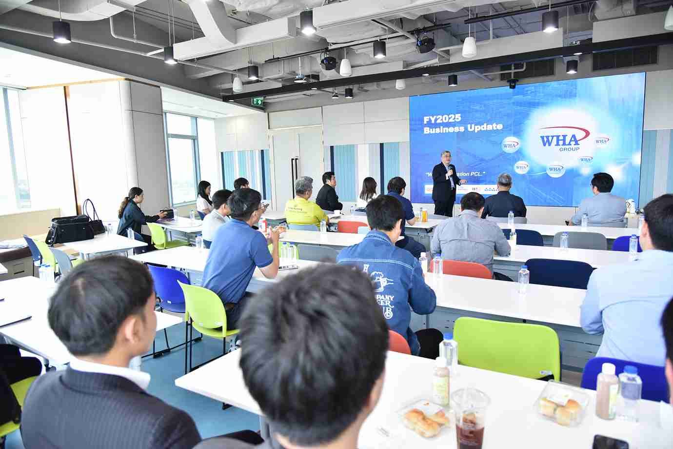 A man presents to an audience seated at tables during a business update.